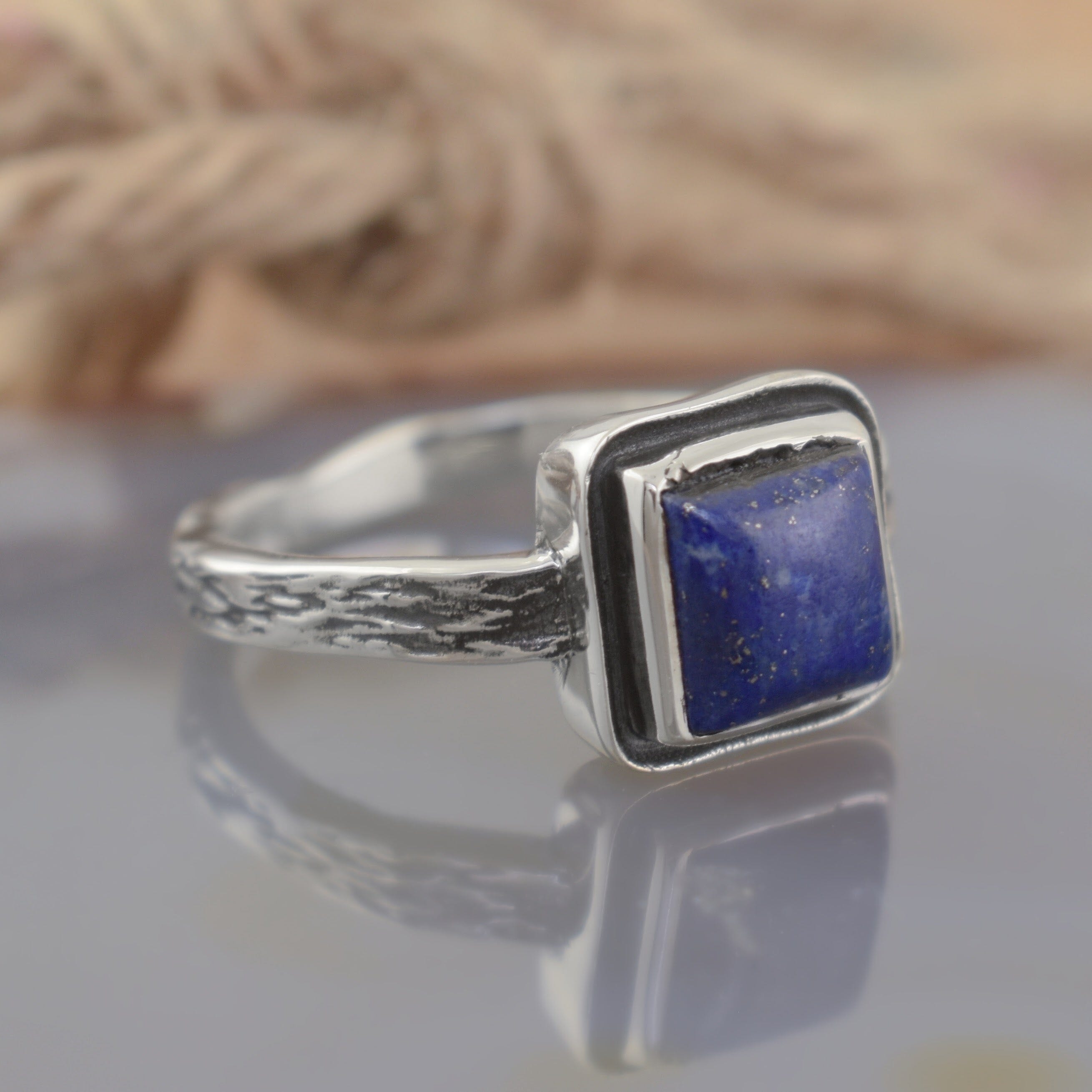 A sterling silver ring featuring a square dark blue stone in the center