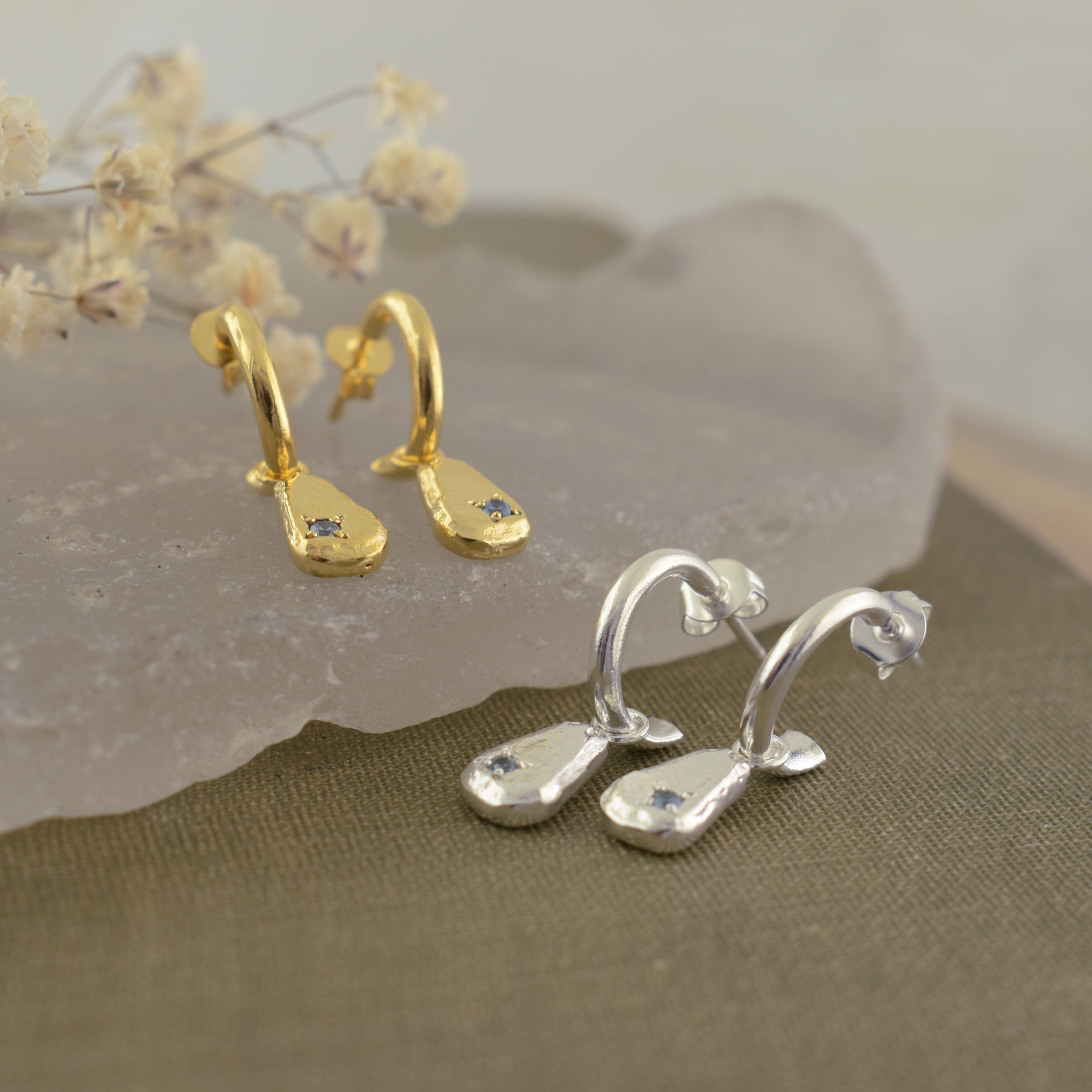 silver and gold brass earrings with a blue cz