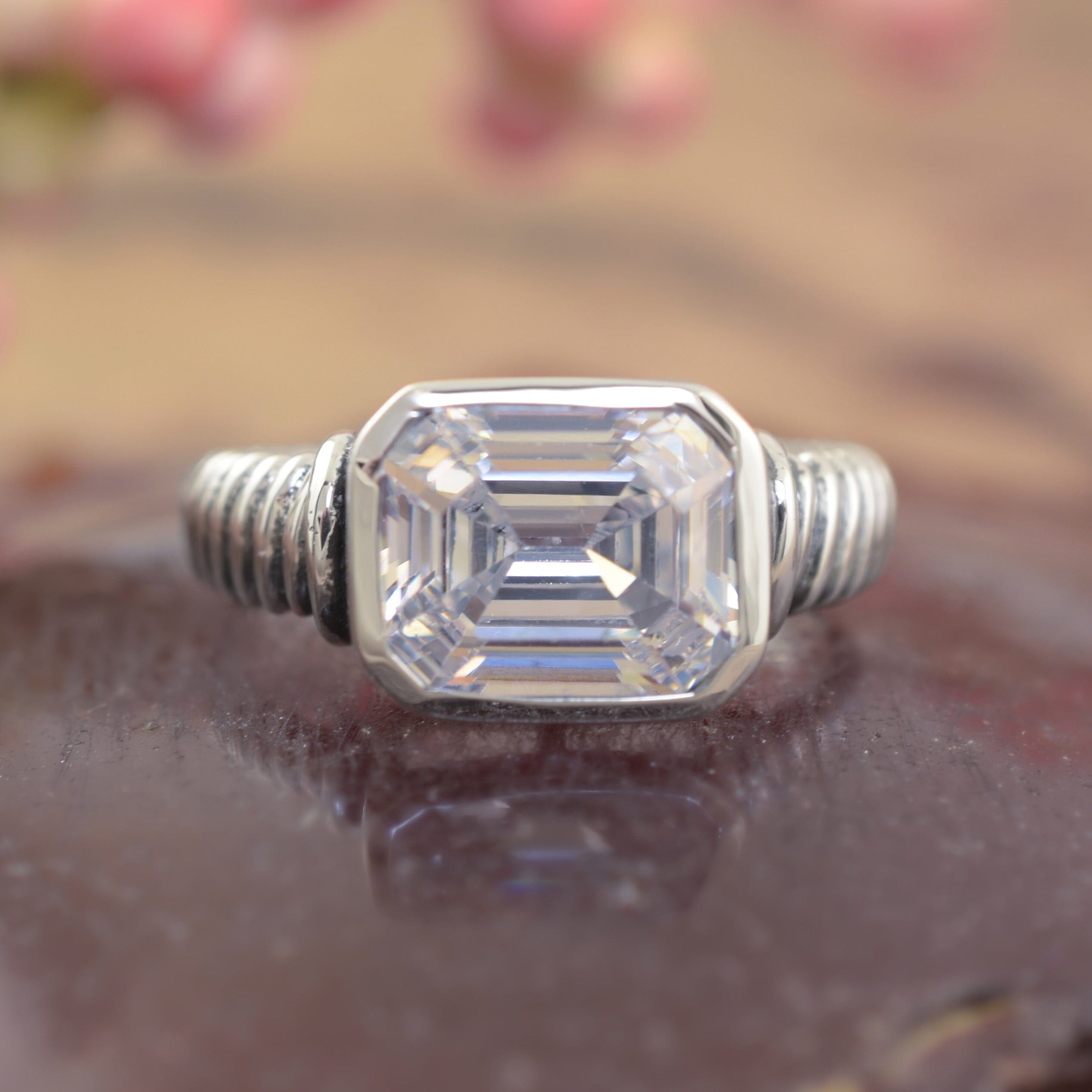 A sterling silver ring with a twisted band, featuring a large asscher-cut clear CZ