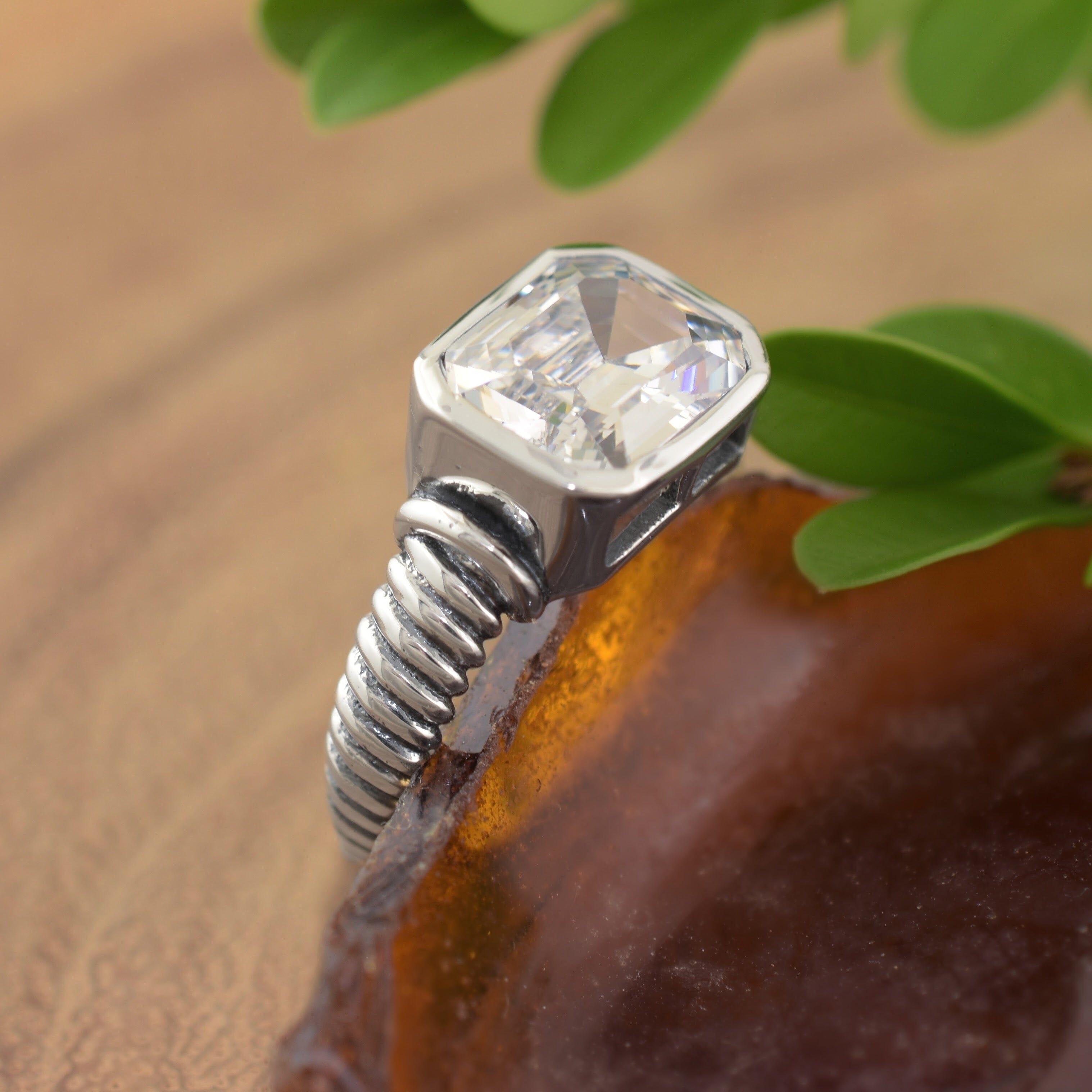 A sterling silver ring with a twisted texture band, featuring an asscher-cut clear CZ