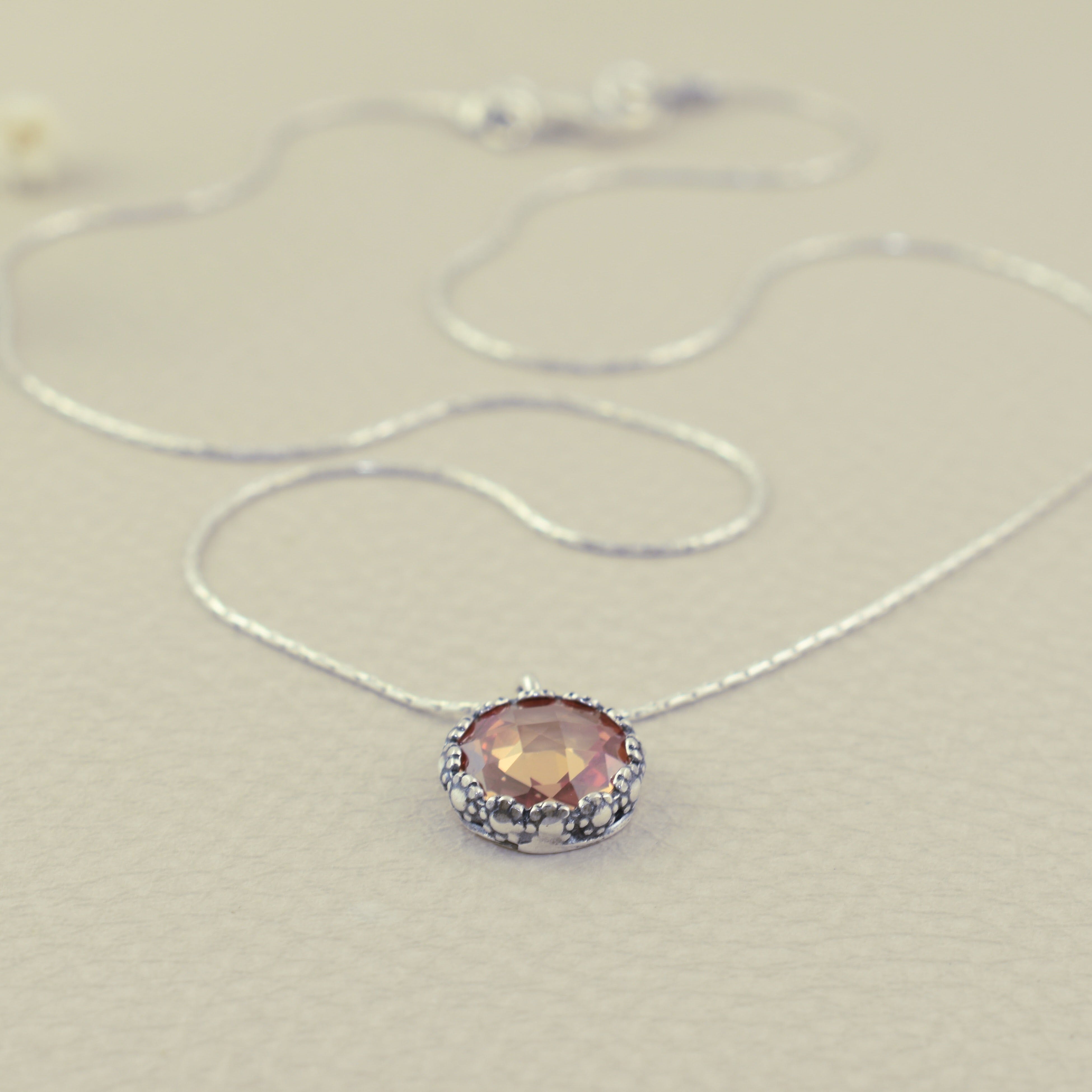 dainty silver necklace with a floral bezel and butterscotch cz center