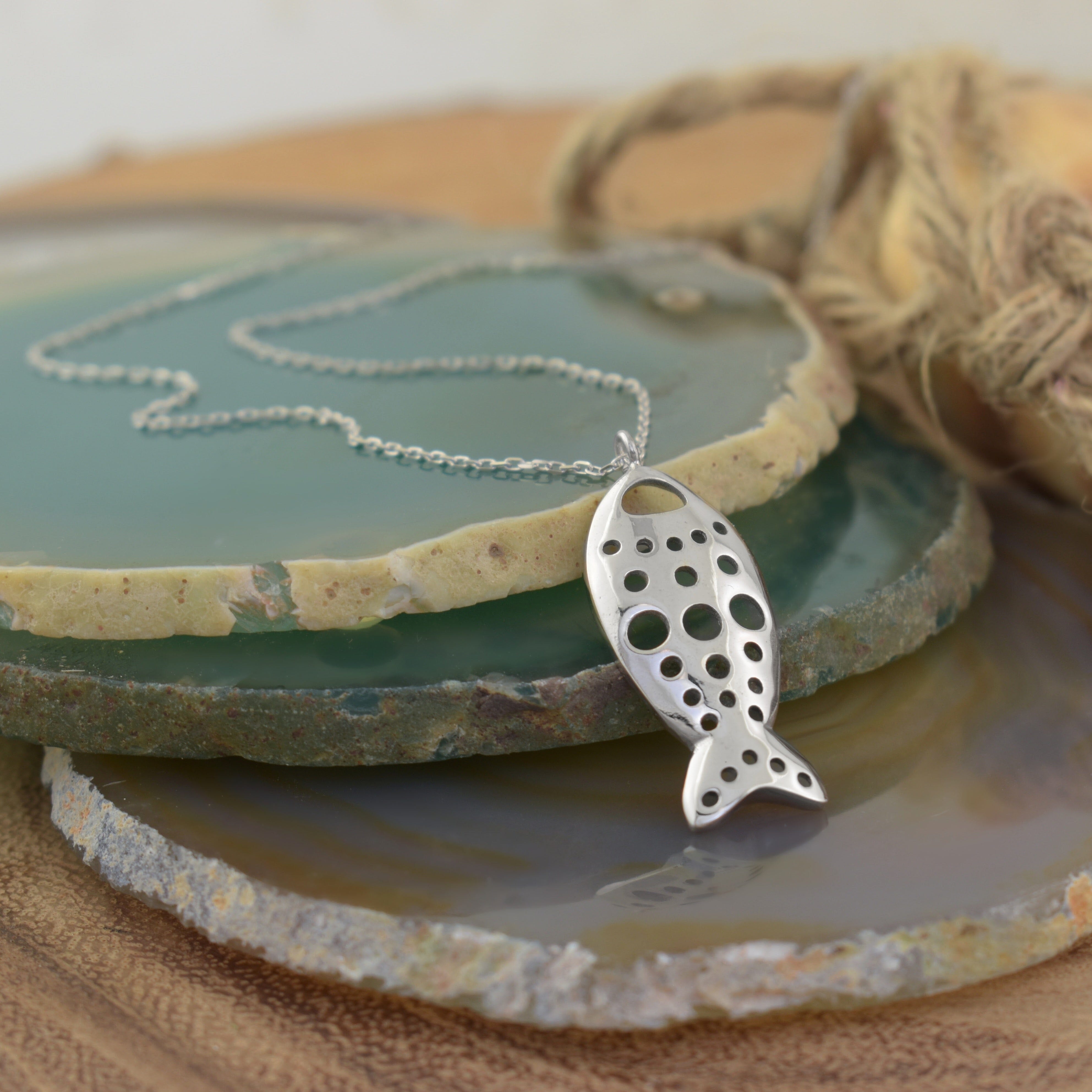 a smooth sterling silver fish-shaped pendant necklace with circular cutouts