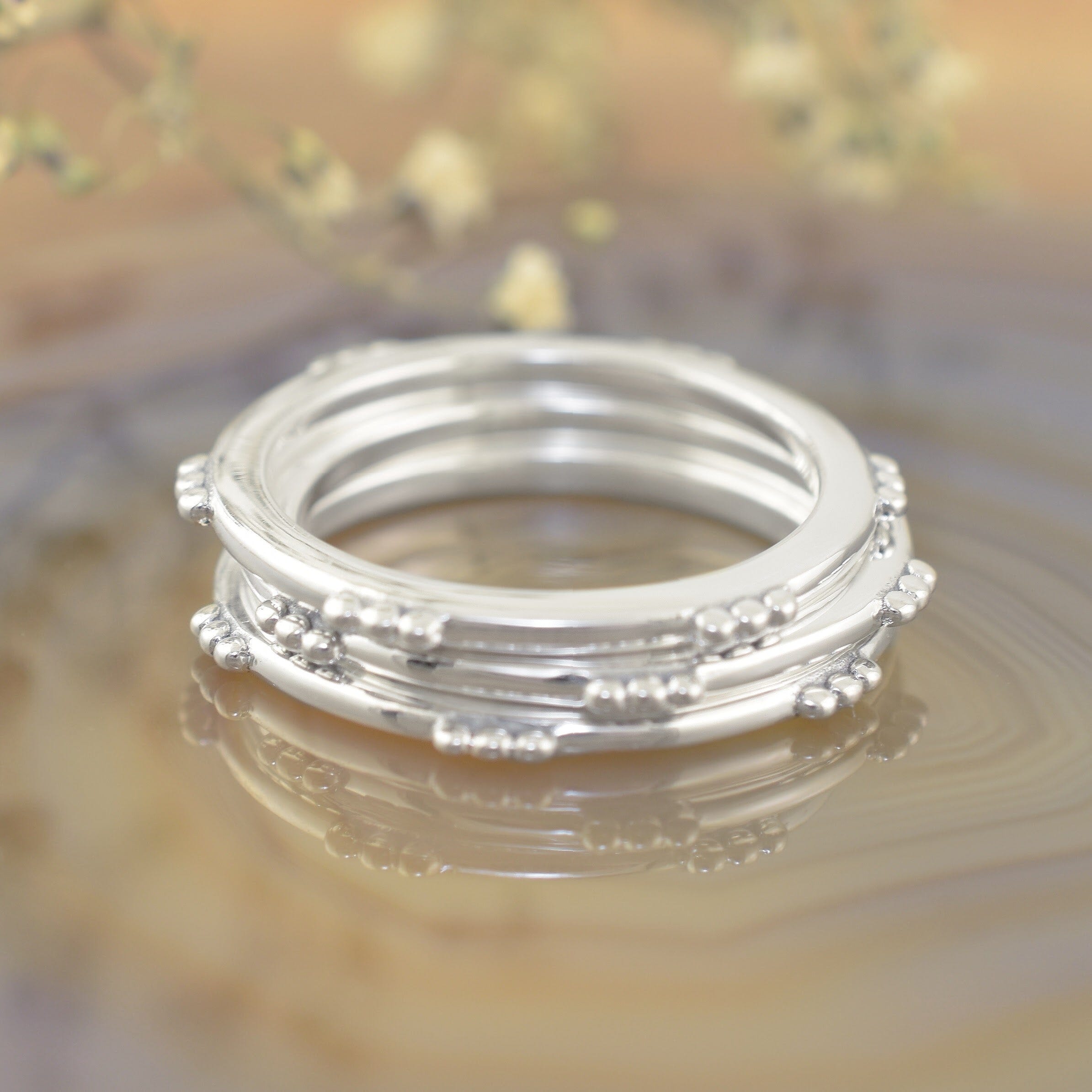 A stack of sterling silver rings featuring small clusters of dots along the outer rim of the rings