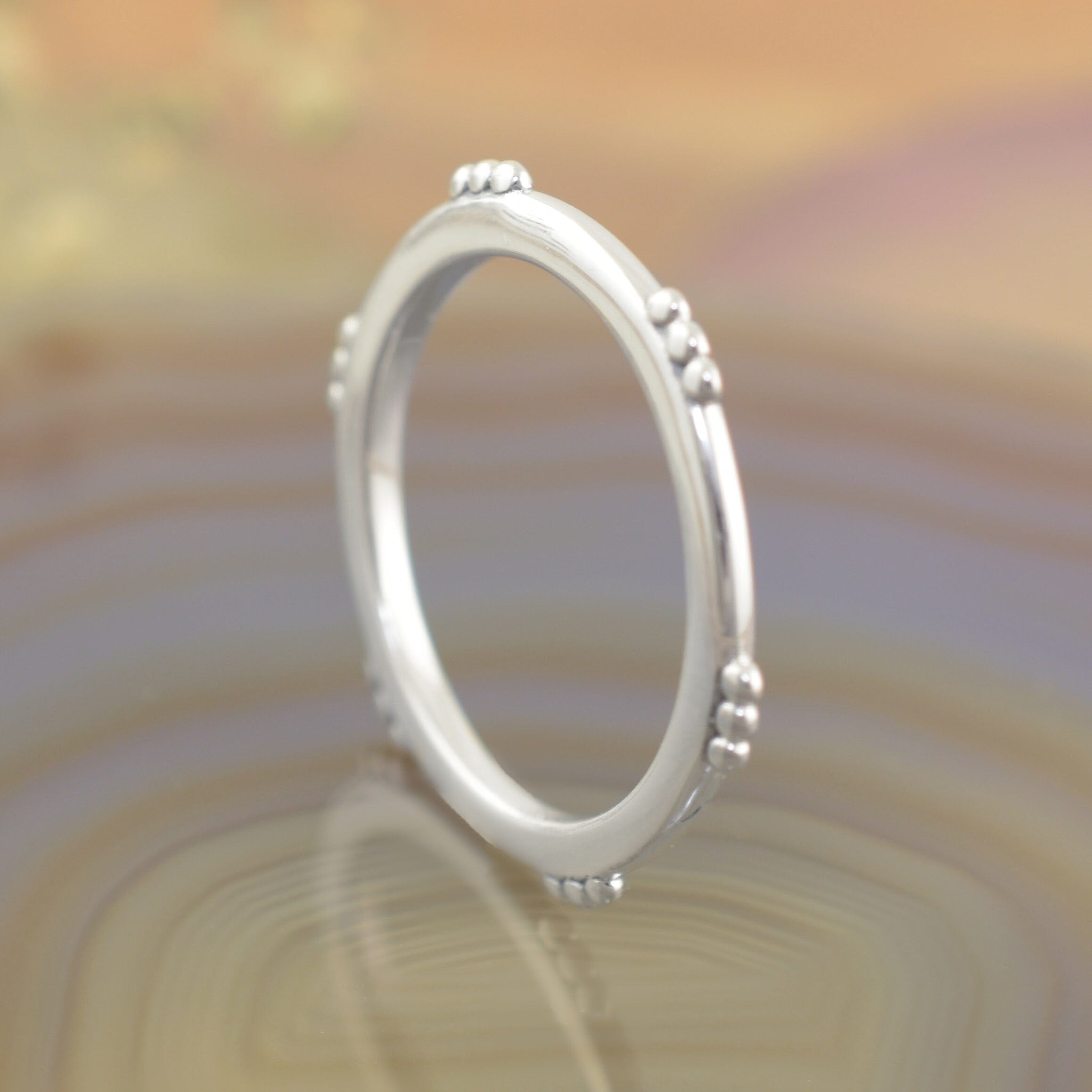 A sterling silver ring featuring small clusters of dots along the outer rim of the ring