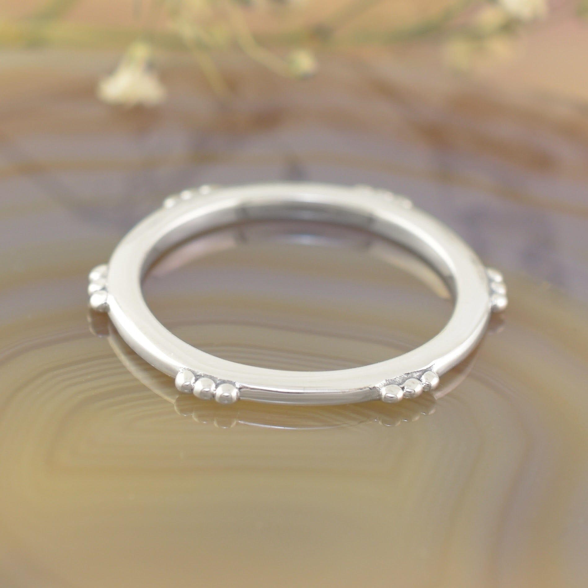 A sterling silver ring featuring small clusters of dots along the outer rim of the ring
