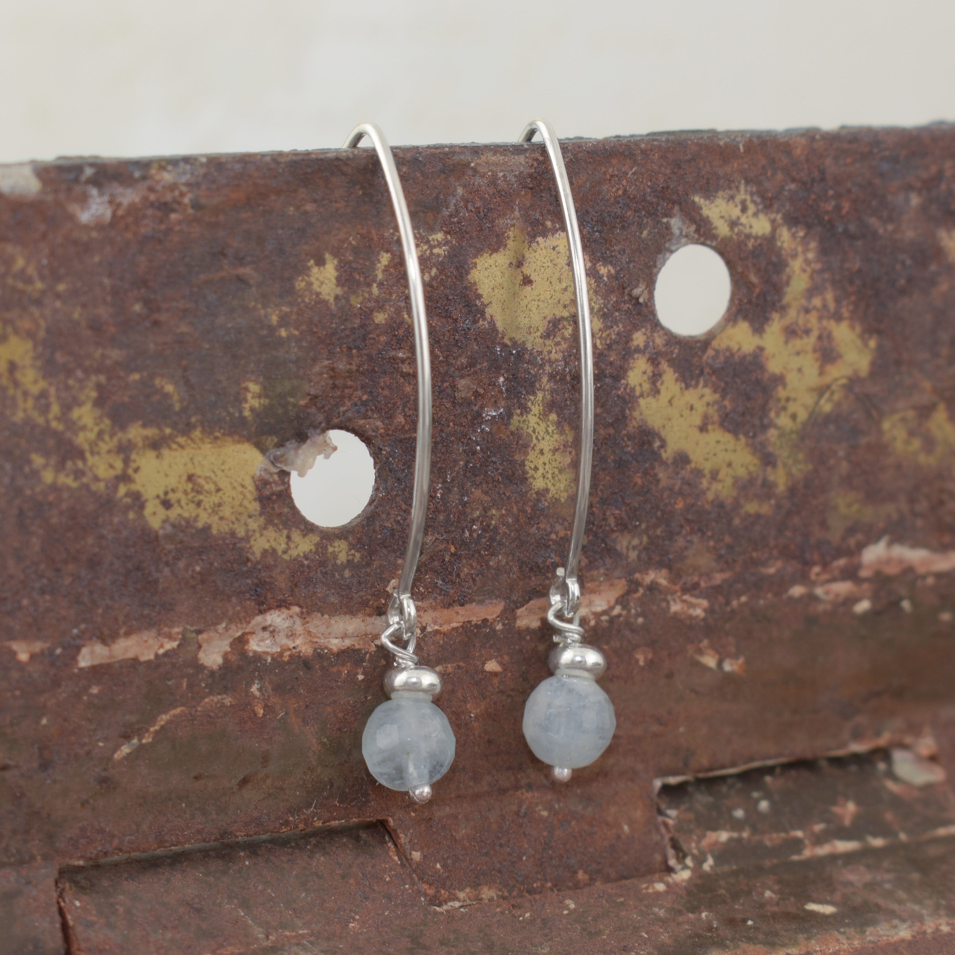 A pair of sterling silver hook earrings with small silver bead accents and light blue-gray round drop bead