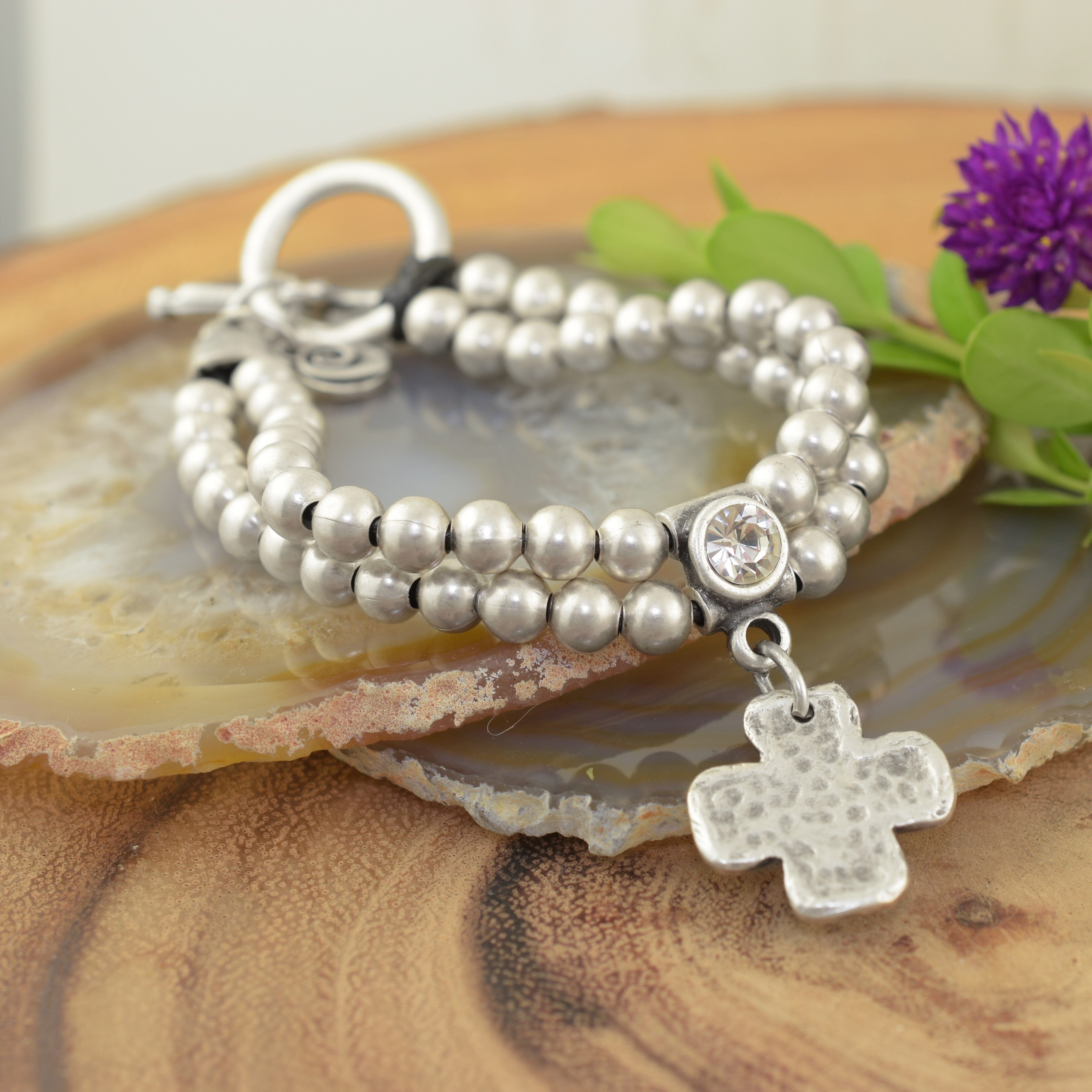 A sterling silver beaded bracelet, featuring a small clear CZ with a cross dangling beneath it