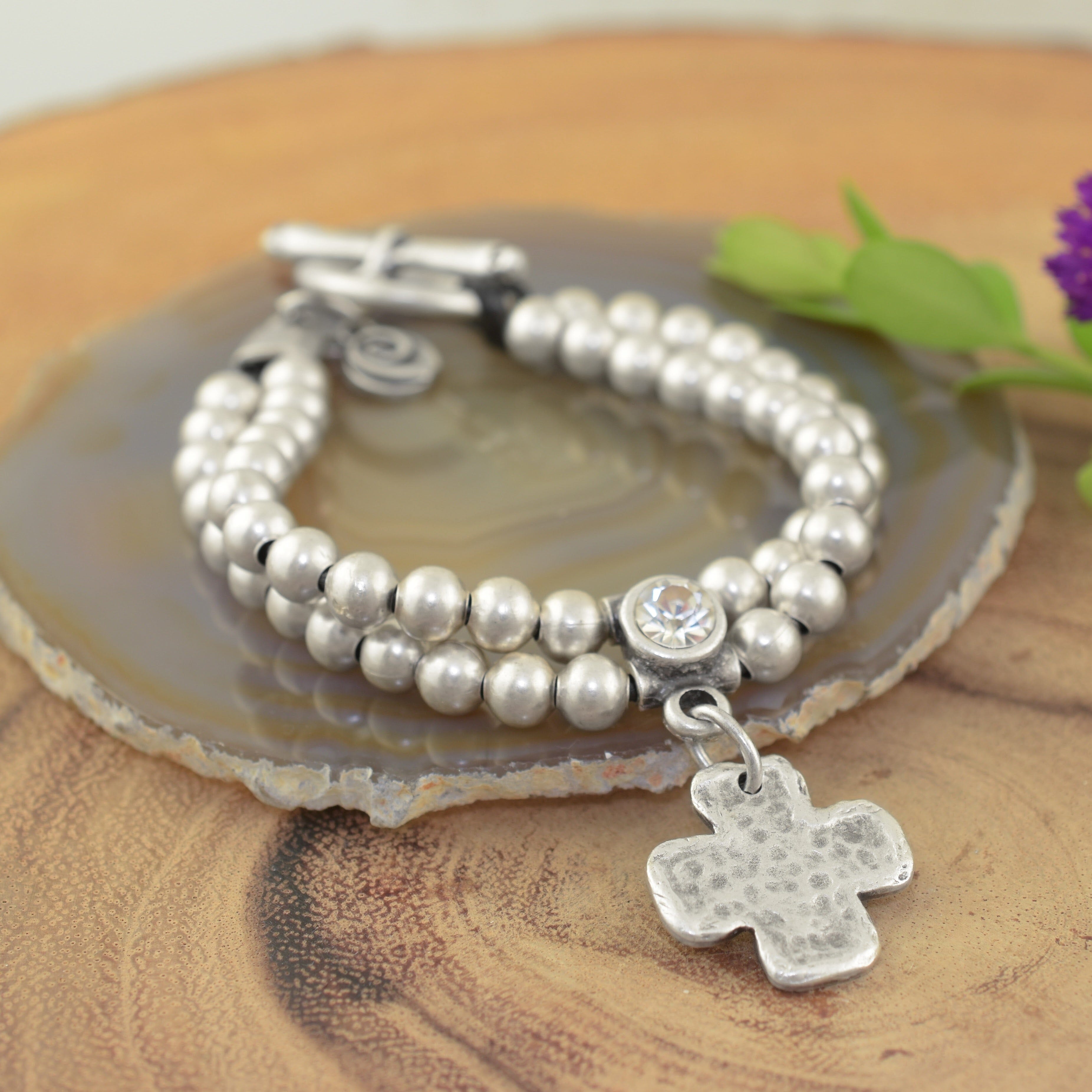 A sterling silver beaded bracelet, featuring a small clear CZ with a cross dangling beneath it