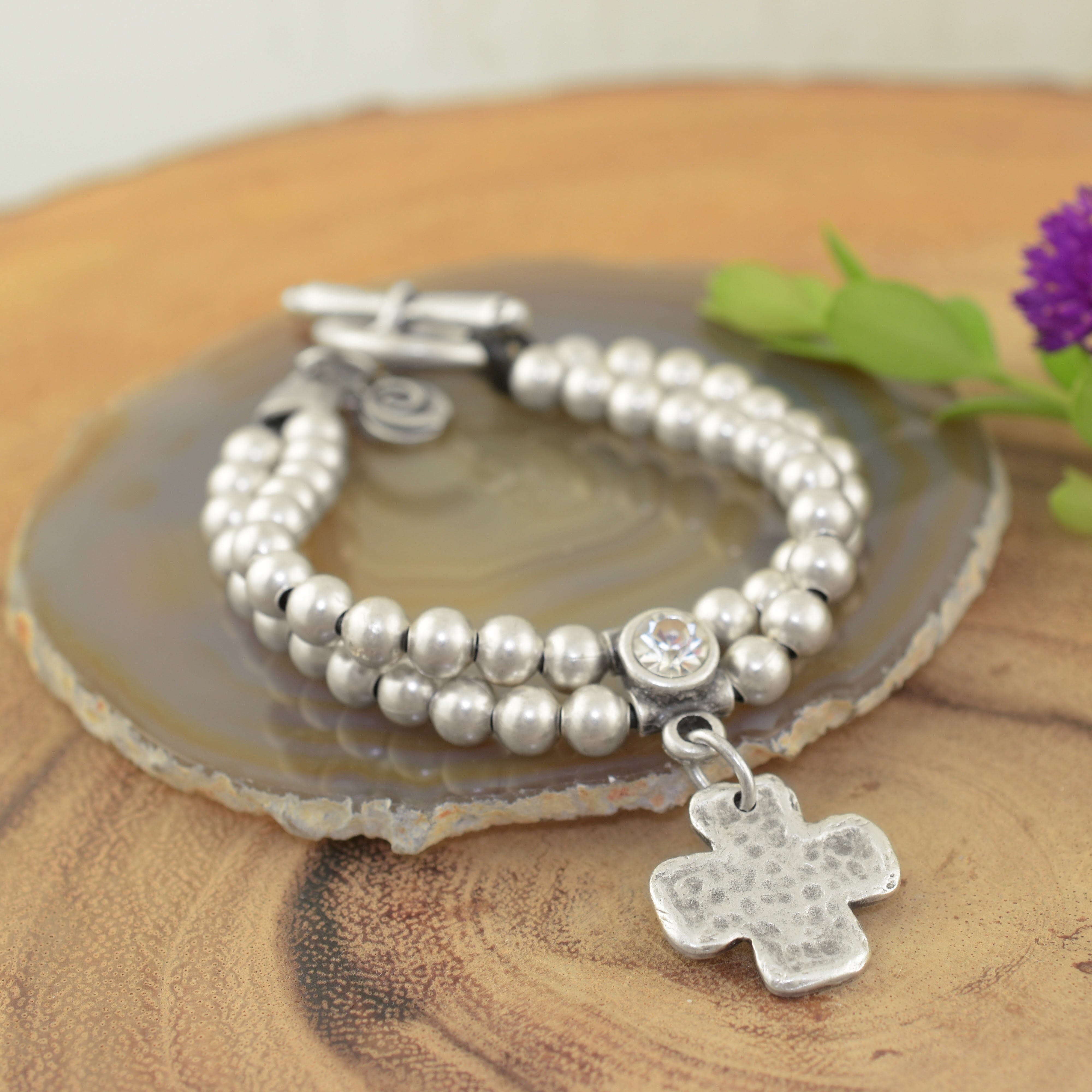 A sterling silver beaded bracelet, featuring a small clear CZ with a cross dangling beneath it