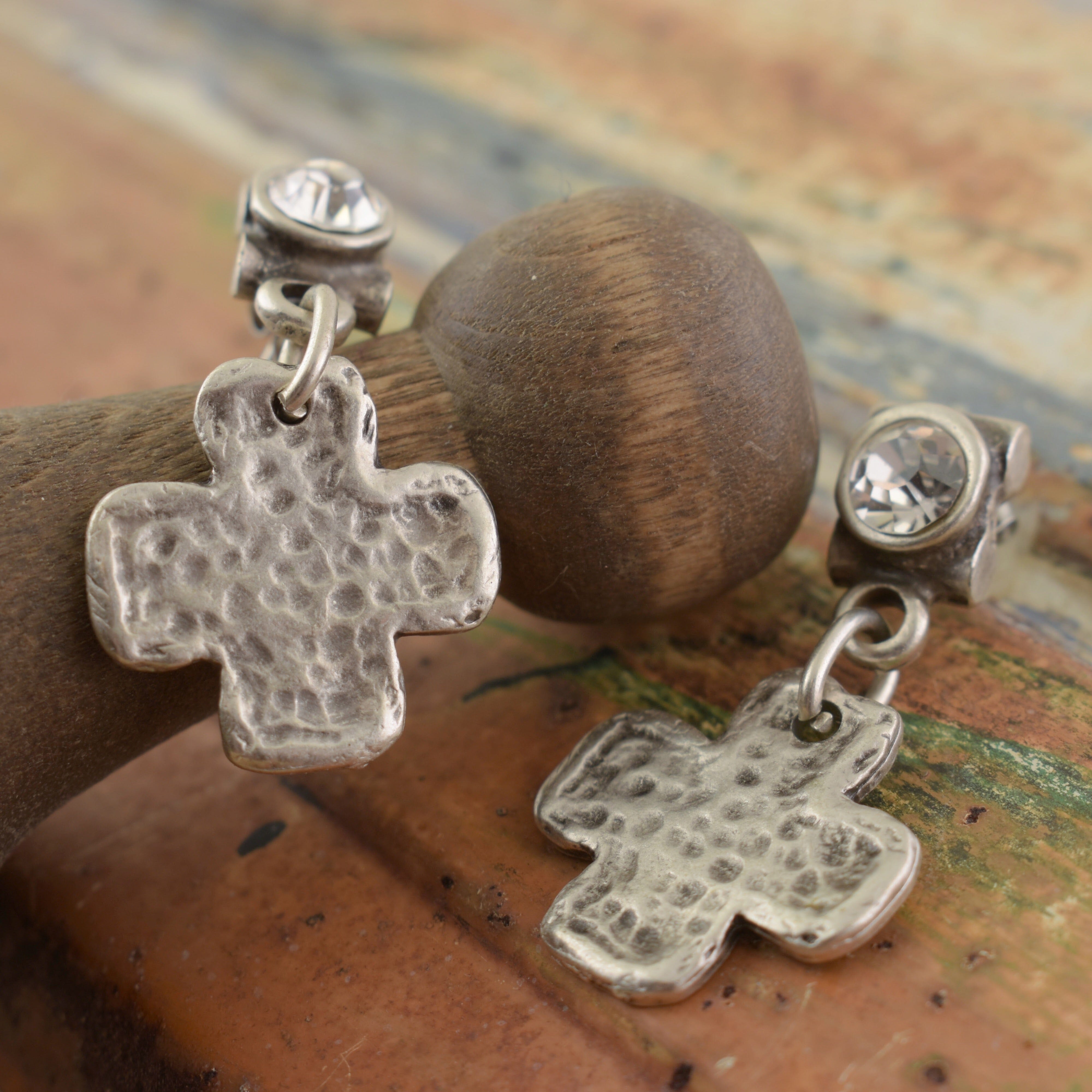 a pair of silver-plated posh boutique earrings, with a CZ post, and a hammered cross hanging from it.