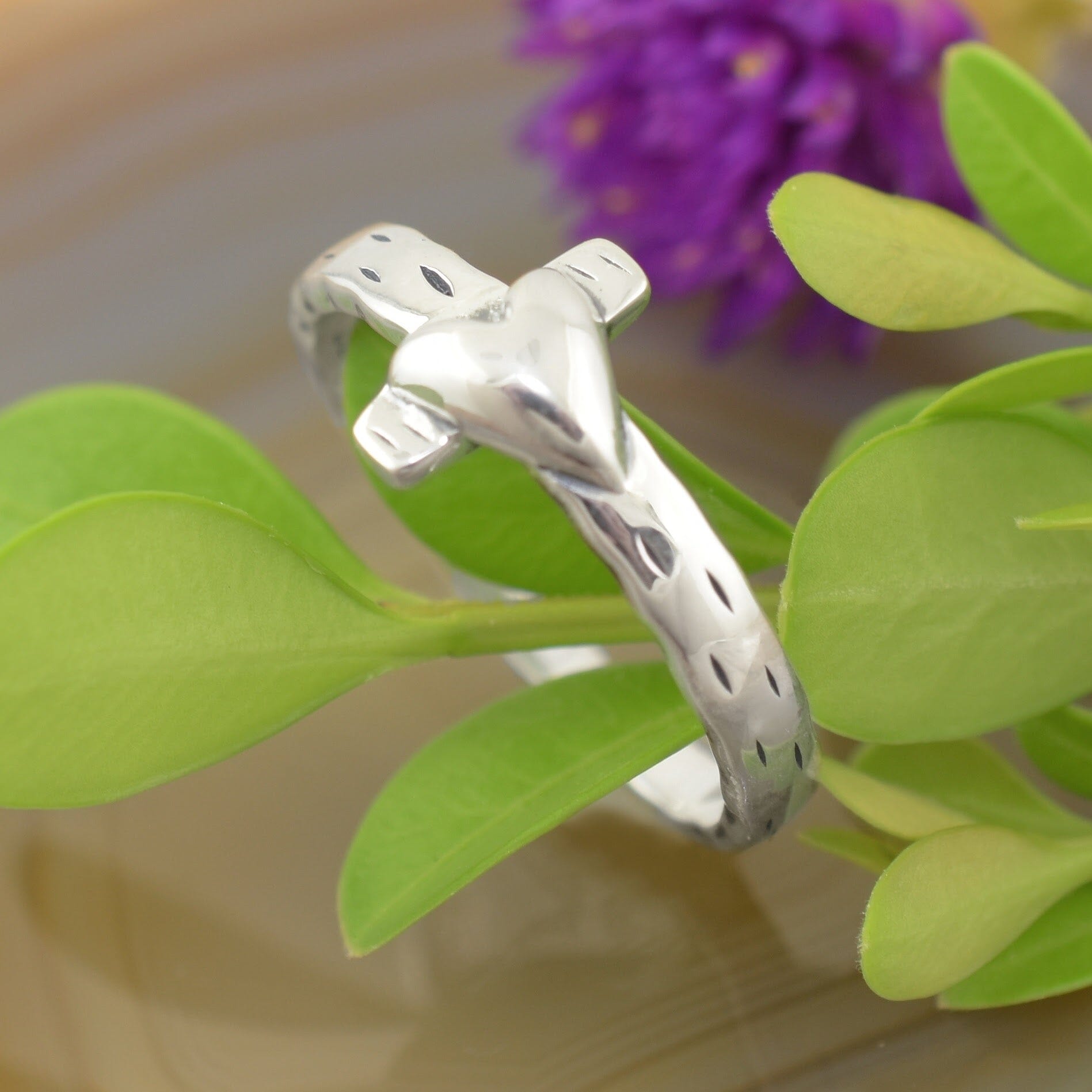 A sterling silver ring with a textured feel, featuring a cross with a small heart laying over top it