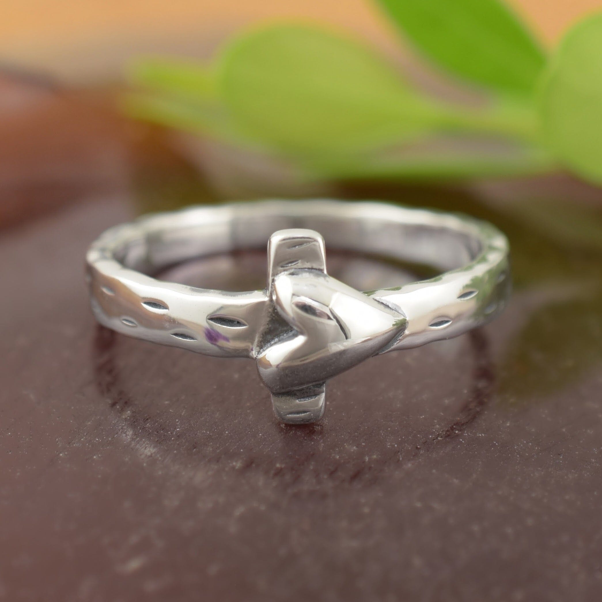 A sterling silver ring with a textured feel, featuring a cross with a small heart laying over top it