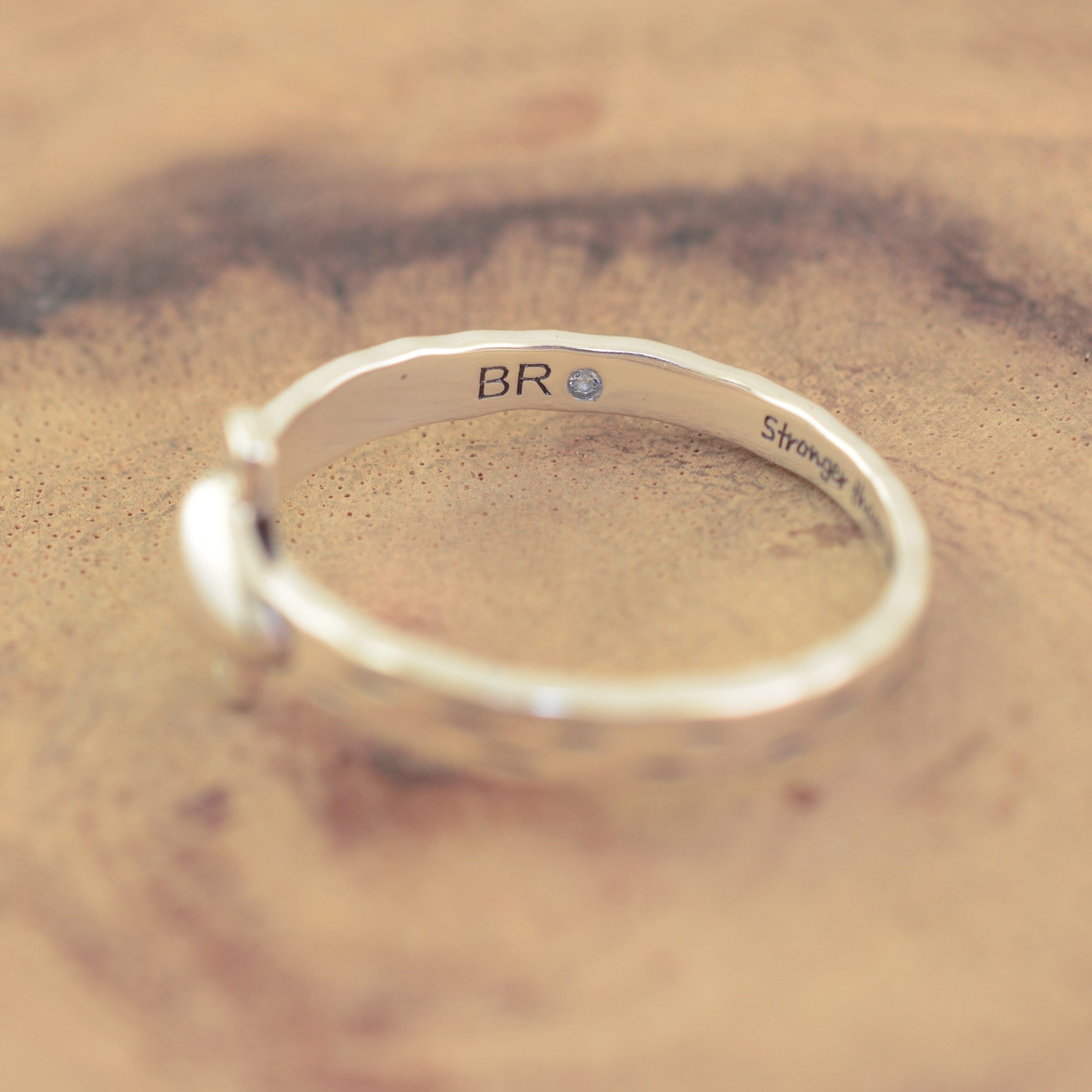 A sterling silver-plated brass ring with a textured finish, featuring the initials 'BR' and a small round clear gemstone on the inside band