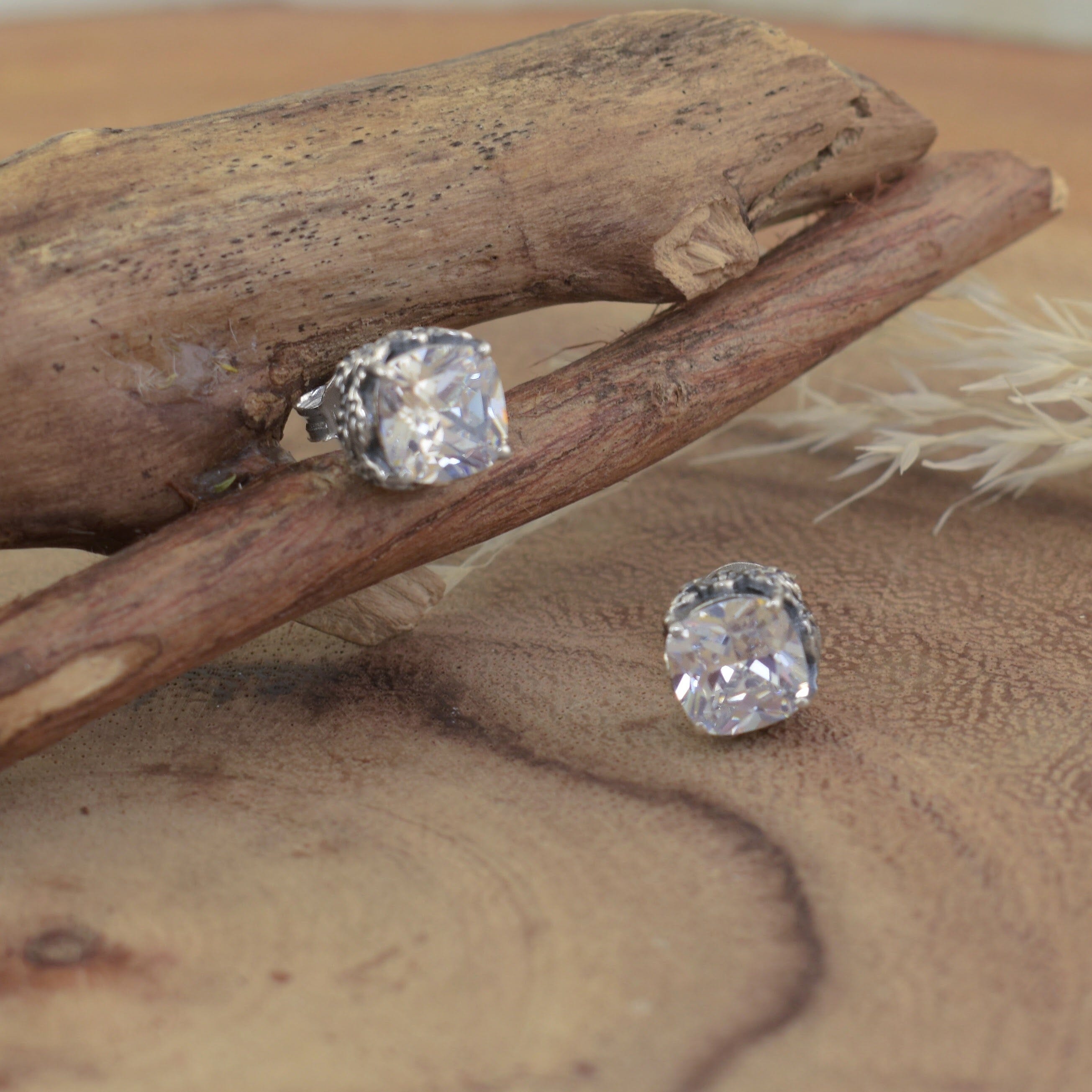 A small pair of sterling silver stud earrings, featuring a square-ish cut clear CZ stone
