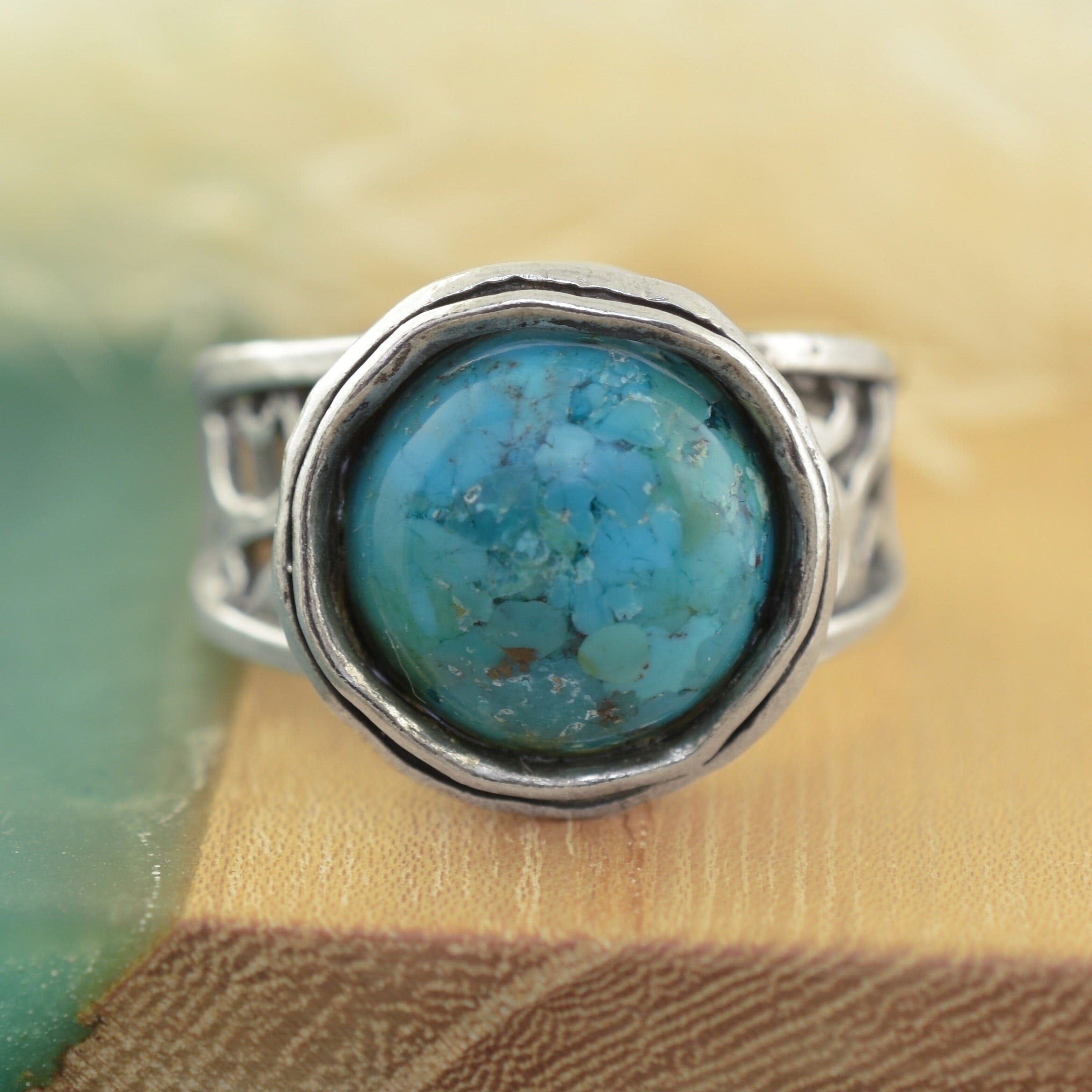 A sterling silver ring featuring a large, round turquoise stone with natural matrix patterns