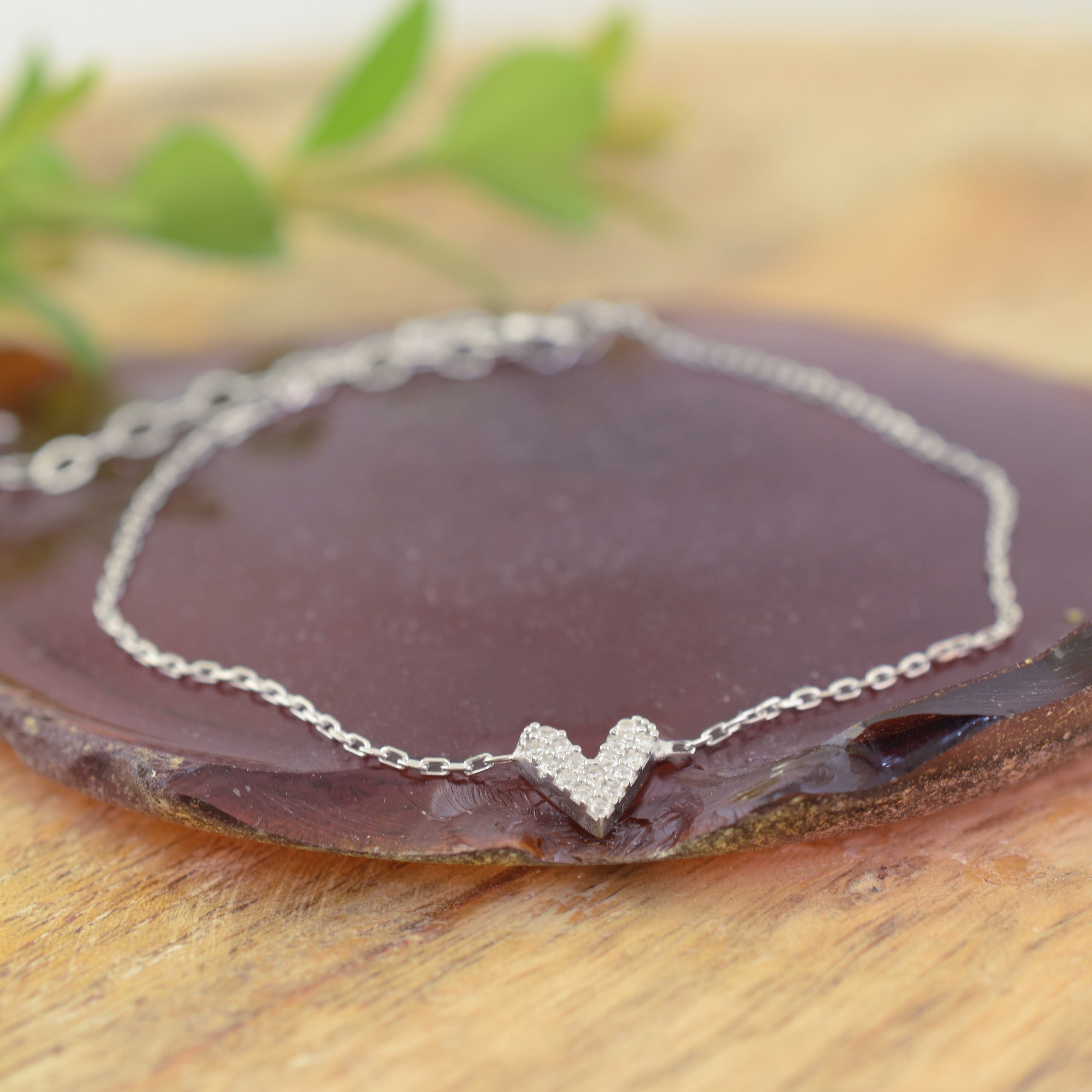 a delicate sterling silver chain bracelet with a small, polished heart pendant with one side covered in tiny clear CZ stones, and the other in a milky white
