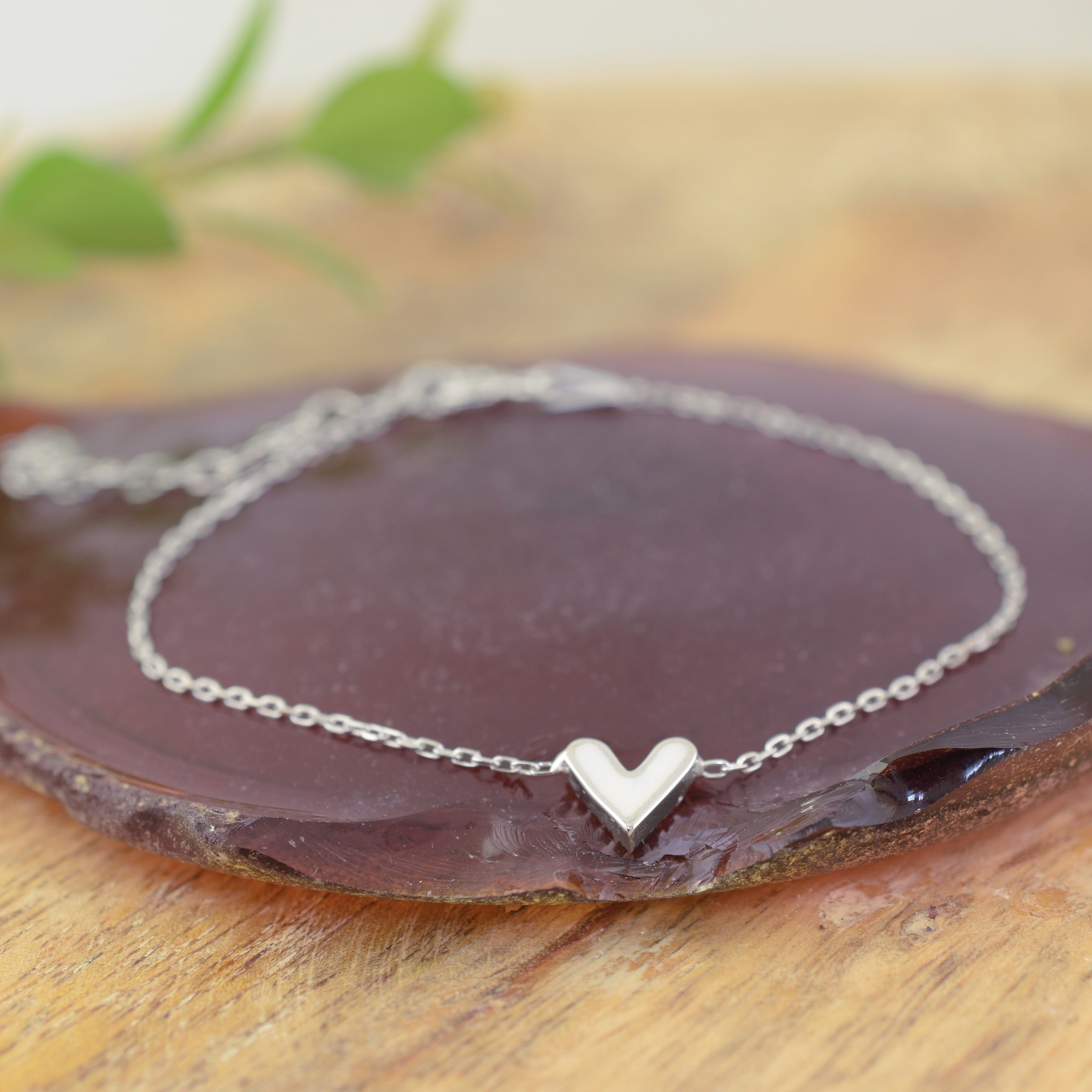 a delicate sterling silver chain bracelet with a small, polished heart pendant with one side covered in tiny clear CZ stones, and the other in a milky white
