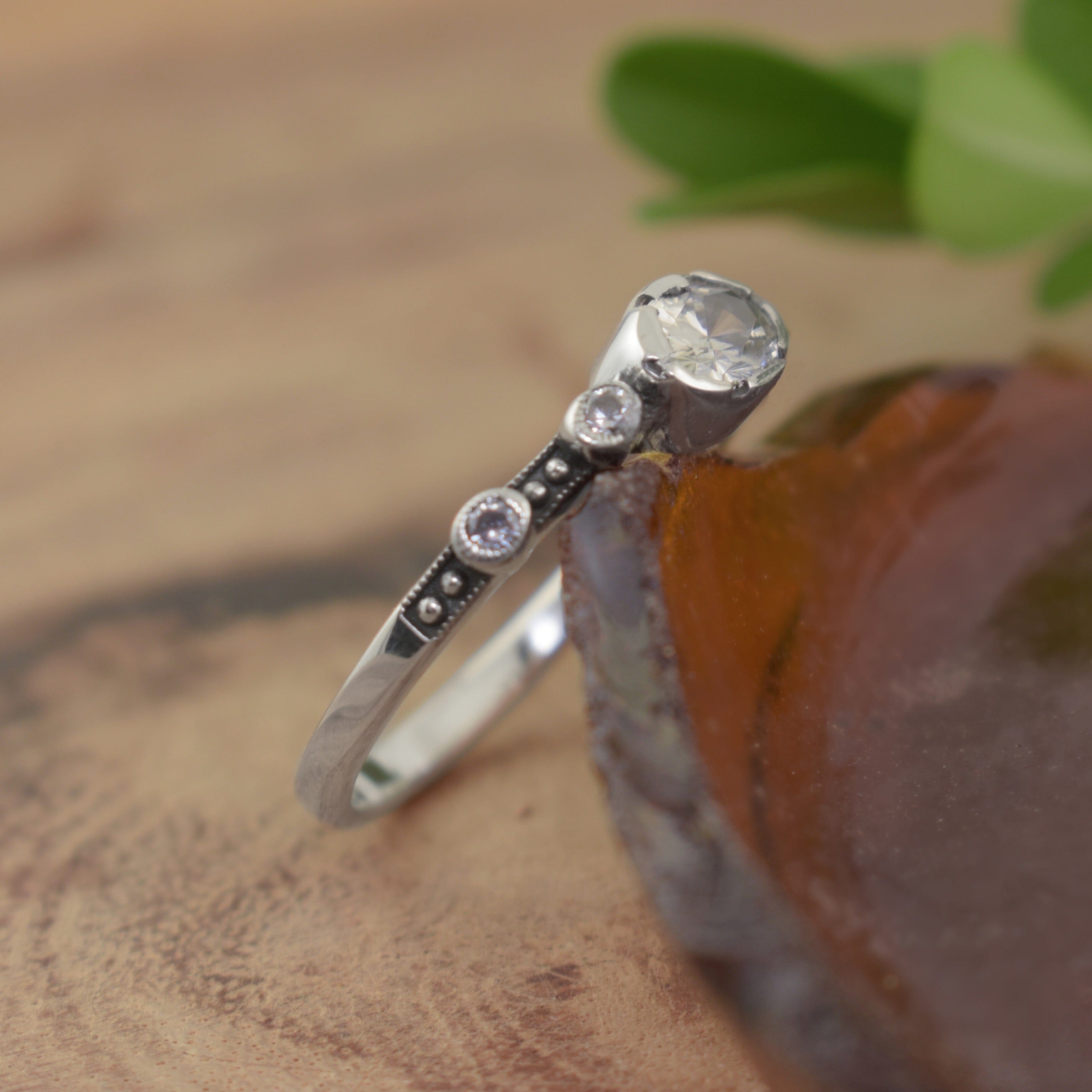 A small sterling silver ring with a large oval CZ stone in the middle and two round CZ stones spaced out along the side