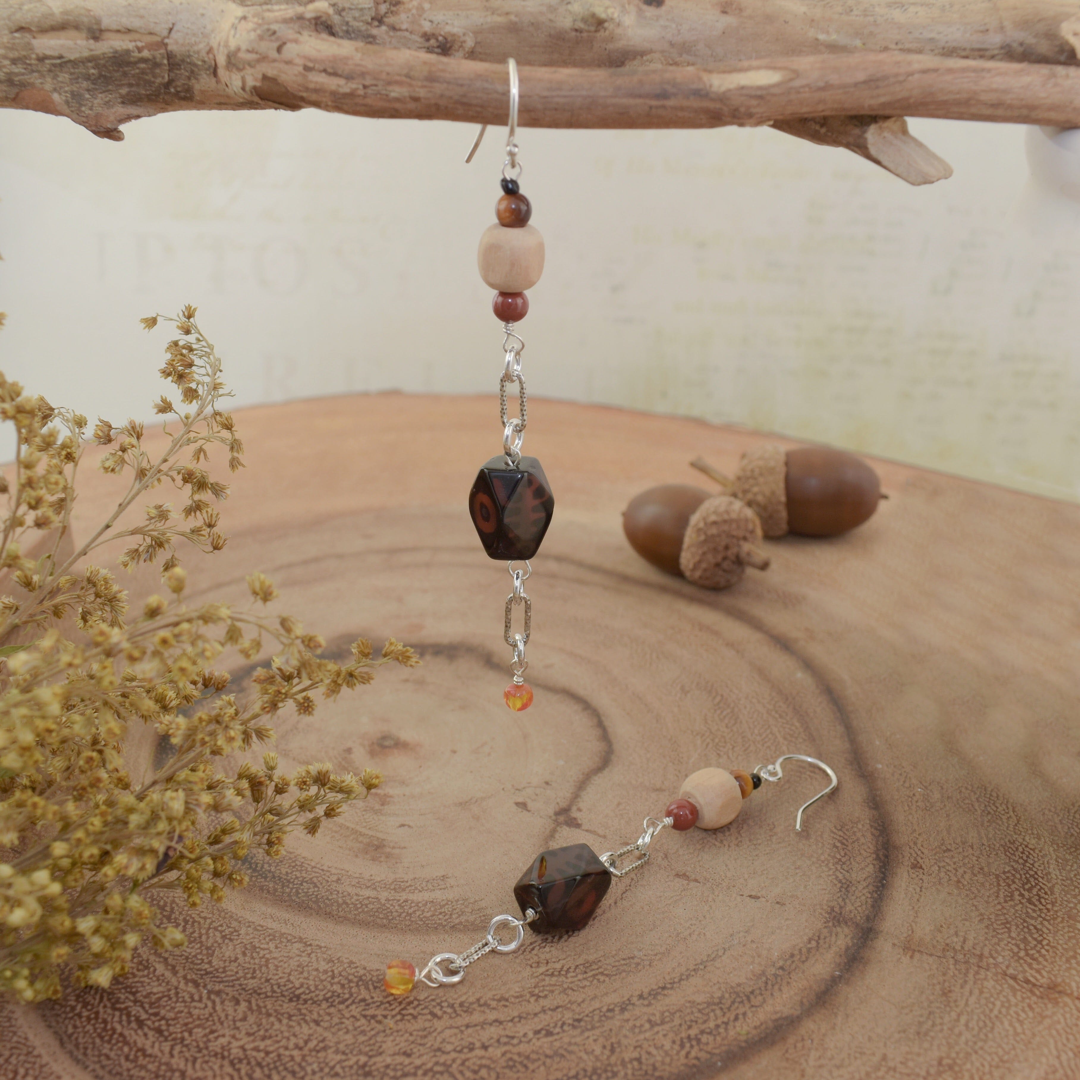 A pair of dangly earrings with sterling silver hooks and multi-colored fall beads