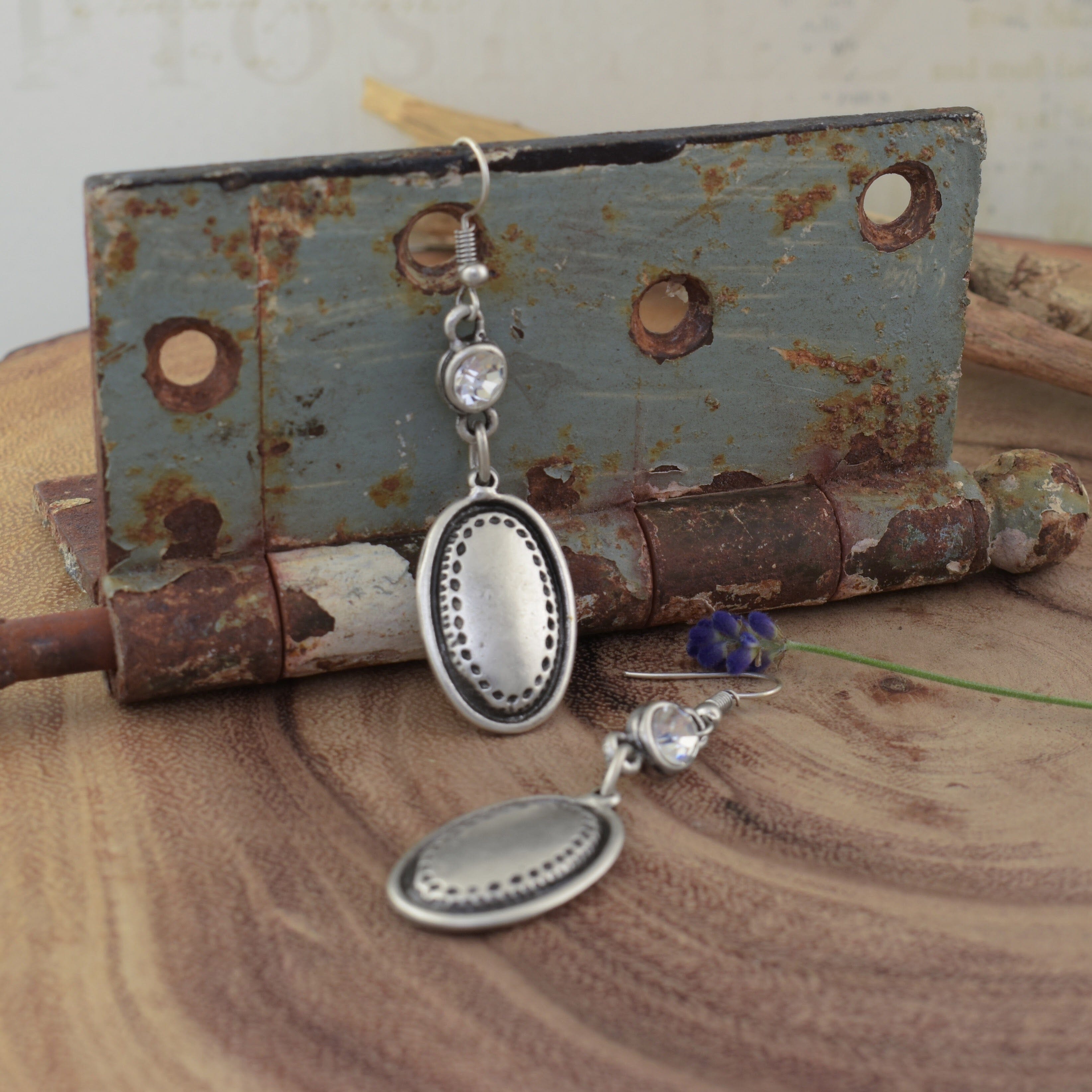 A pair of silver-plated zamak earrings, featuring a round clear CZ stone and a large oval dangling from the hook