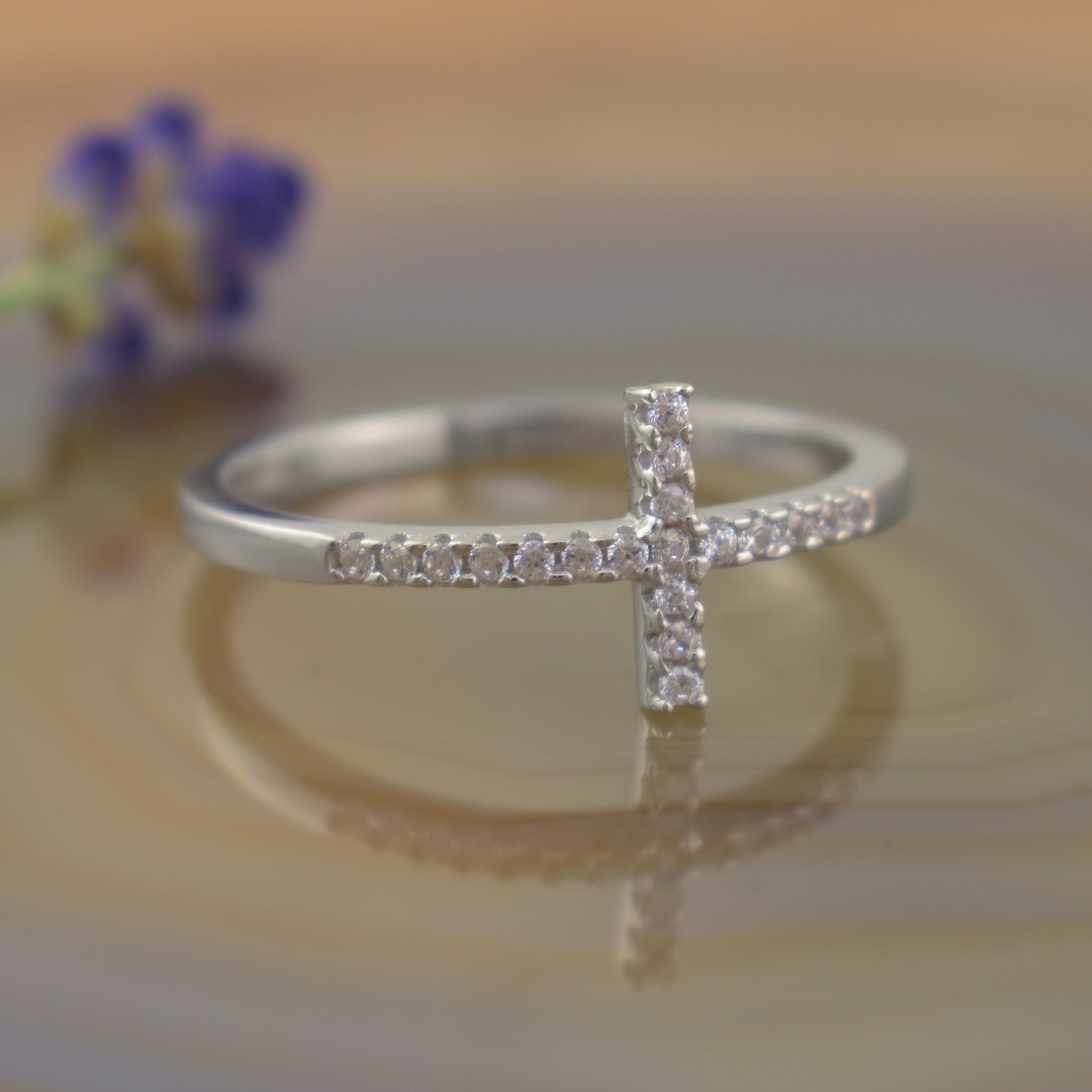 A sterling silver ring featuring a cross shape design lined with clear CZ stones
