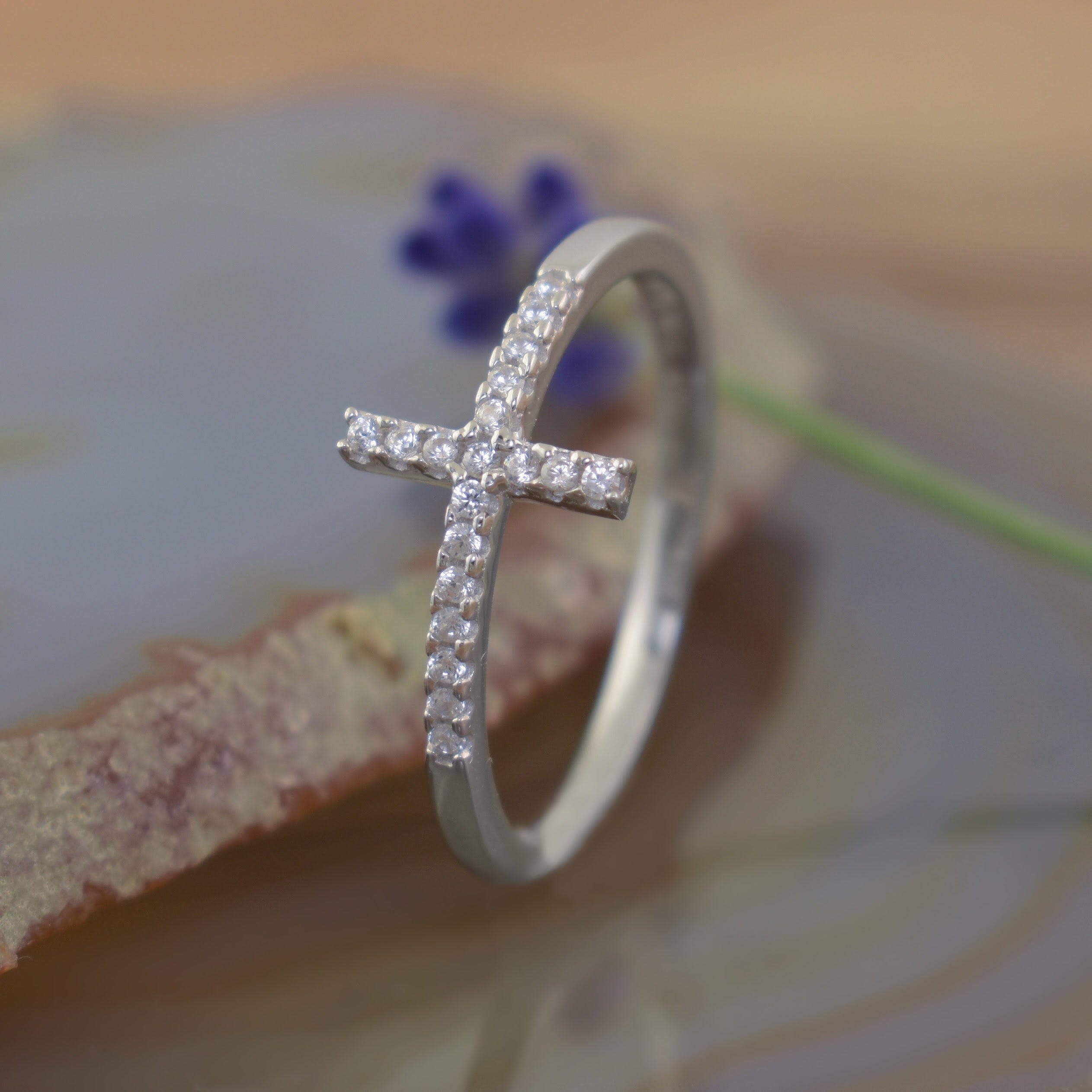 A thin sterling silver ring with a cross design featuring small clear CZ stones lining the cross
