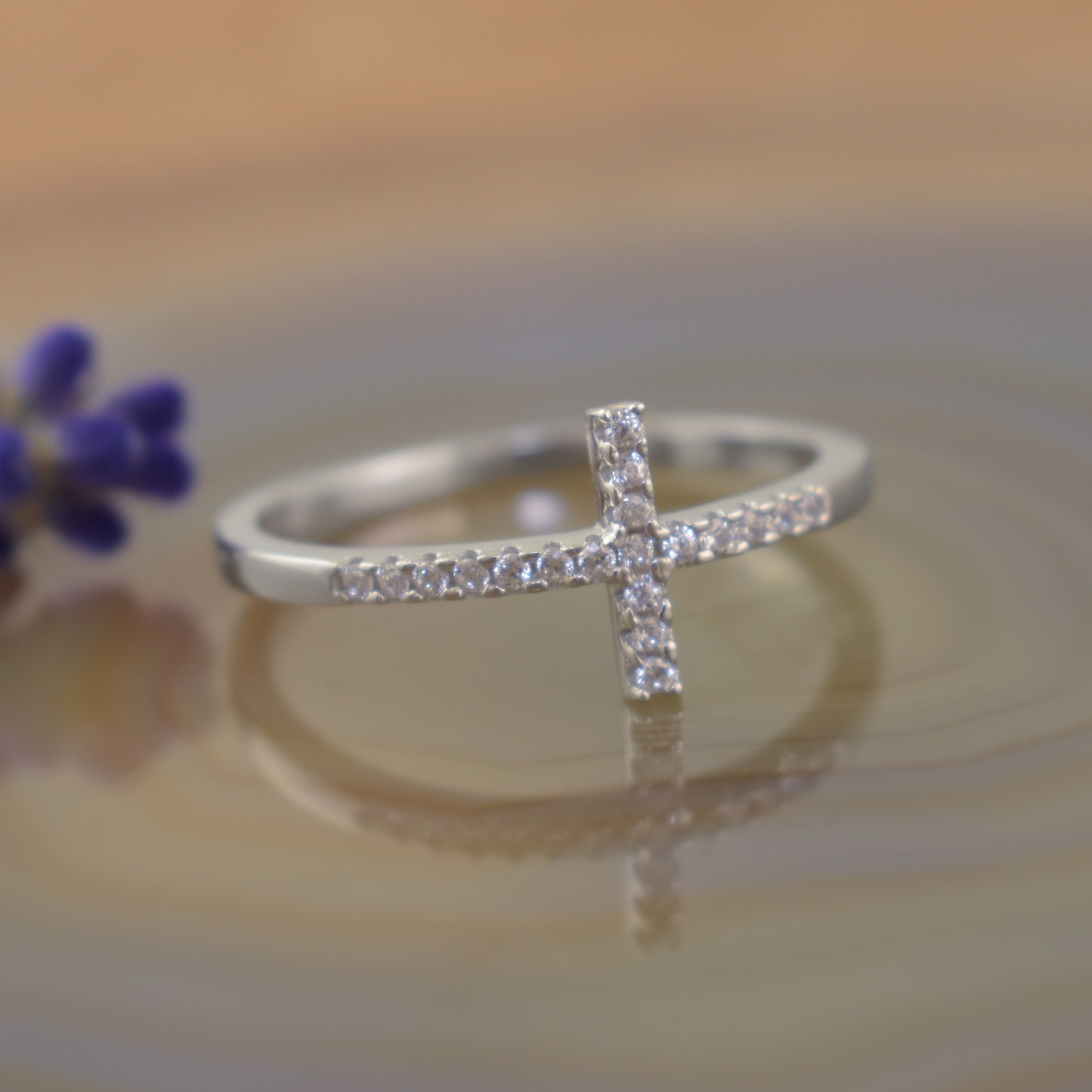 A small sterling silver ring featuring a cross design lined with small clear CZ stones