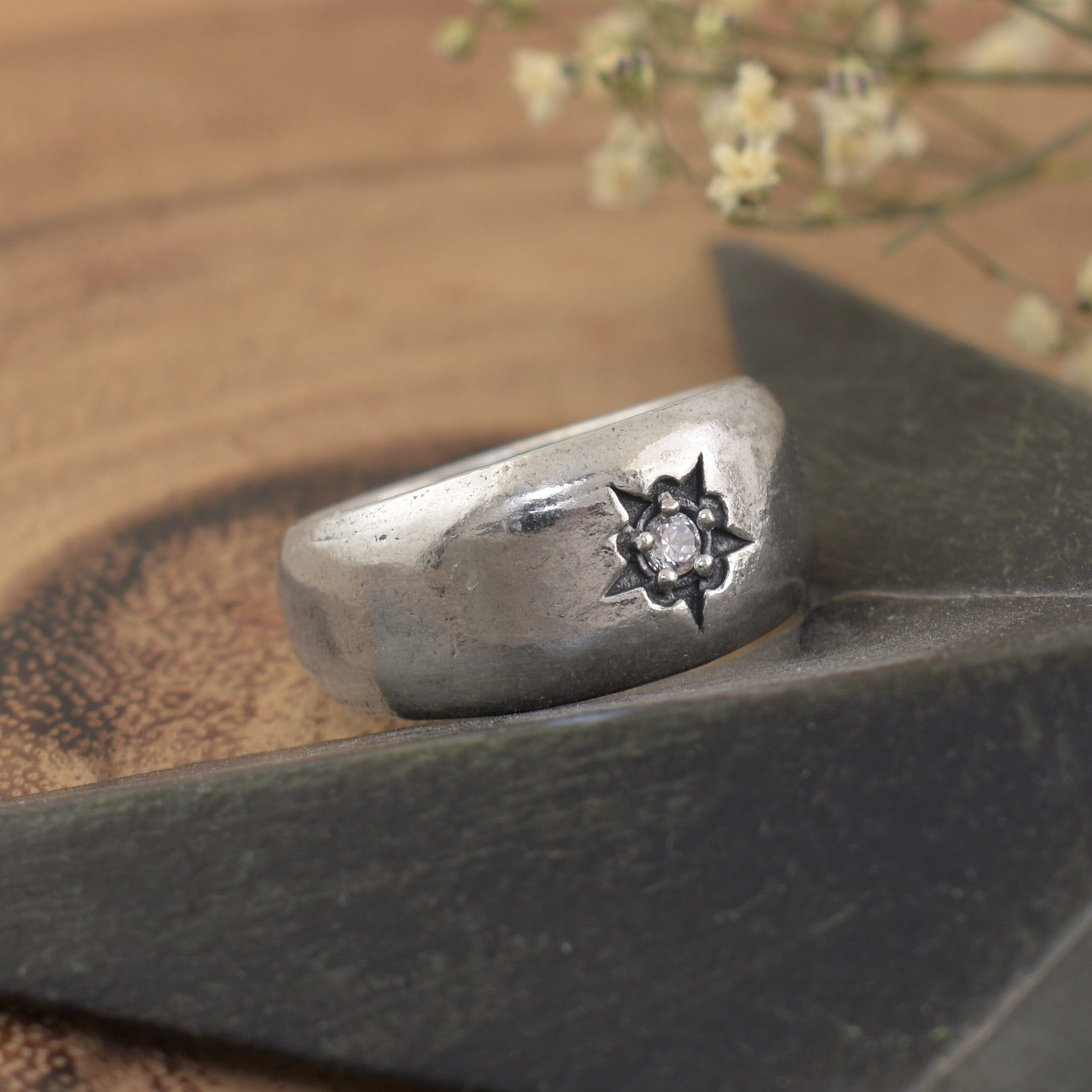 A sterling silver ring featuring a small clear CZ in the center of a starburst design