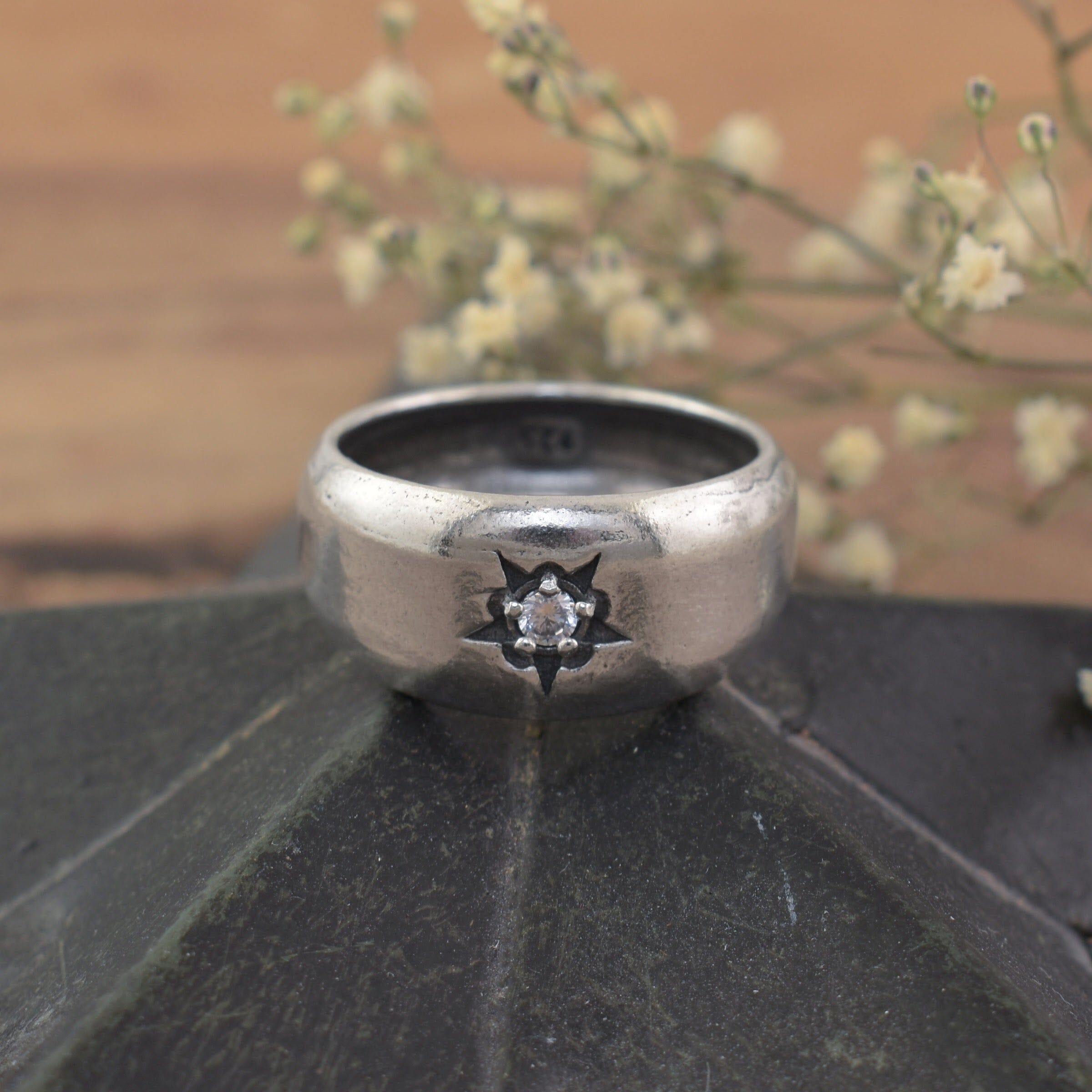 A sterling silver ring featuring a small clear CZ in the center of a starburst design