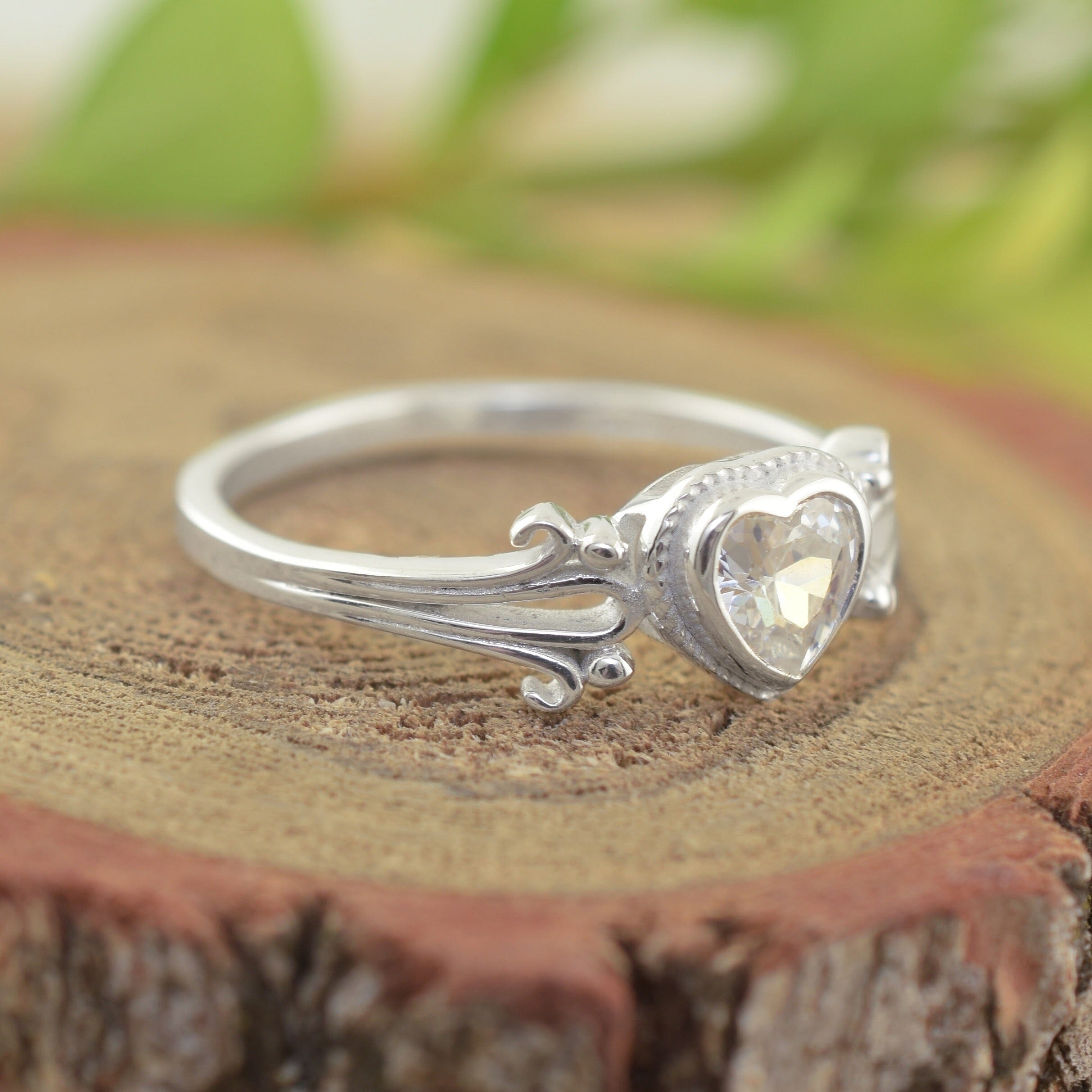 A sterling silver ring with a heart-shaped clear gemstone and a smaller heart on the band