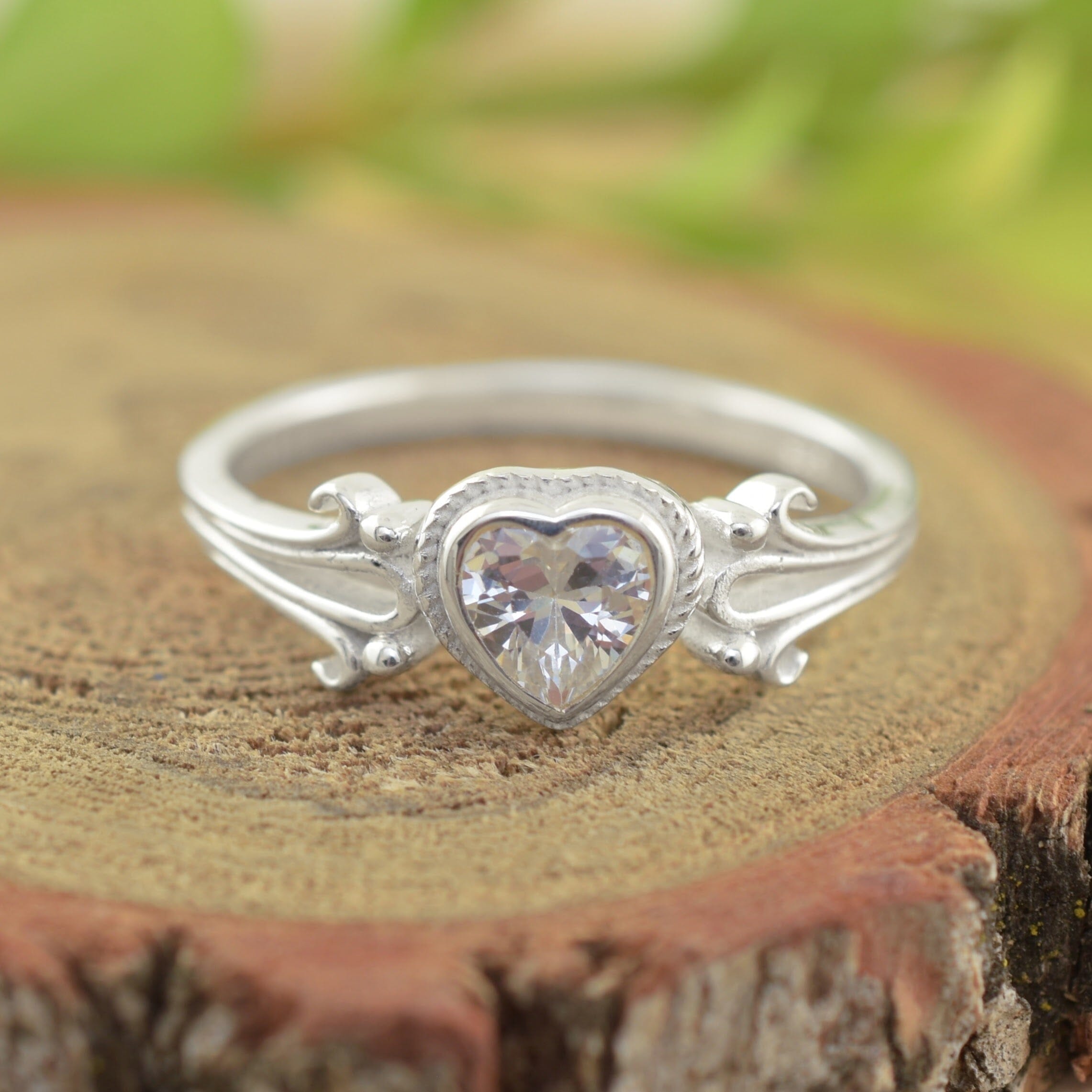A sterling silver heart-shaped ring with a clear faceted gemstone in the center