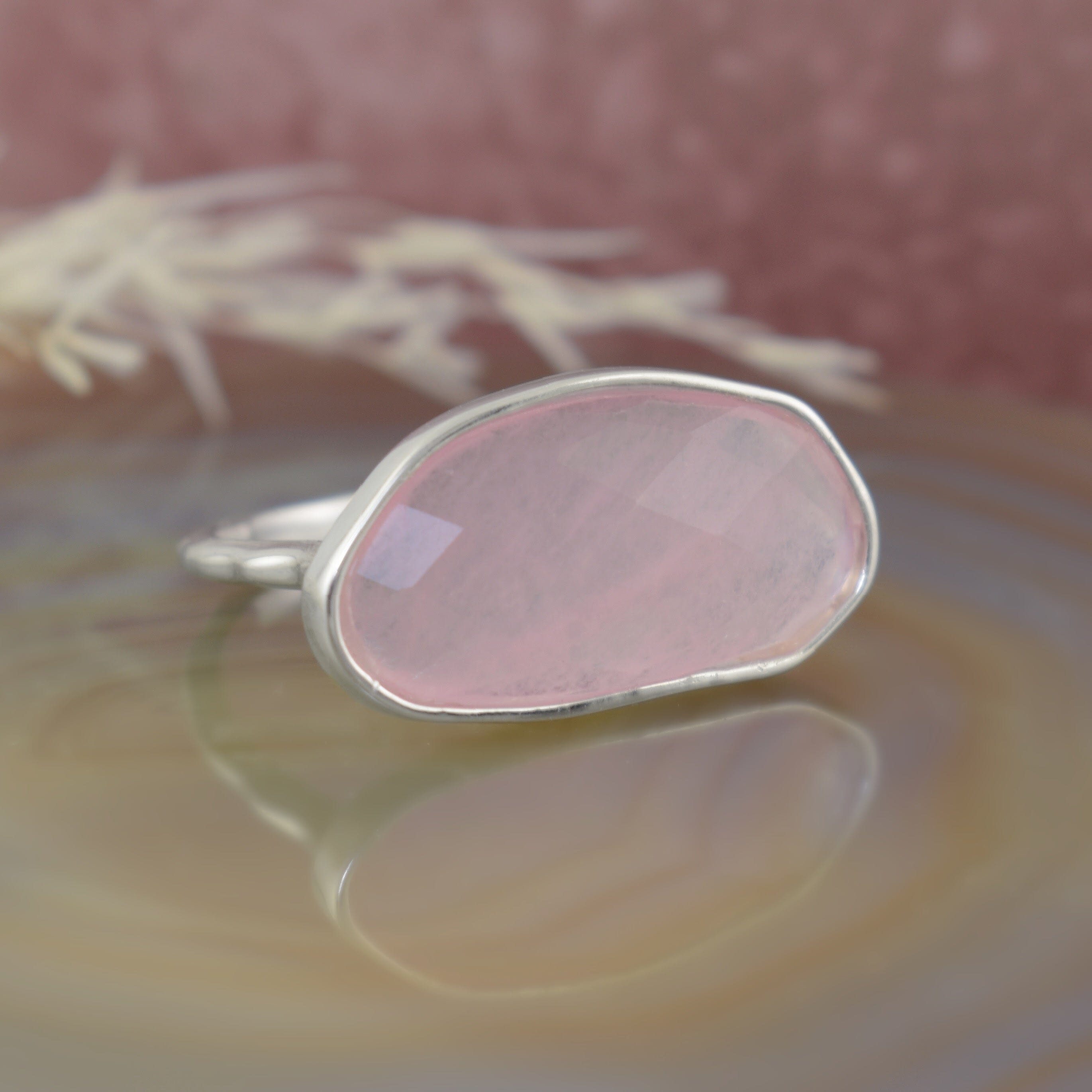 A sterling silver ring featuring an oval pink quartz stone in the center