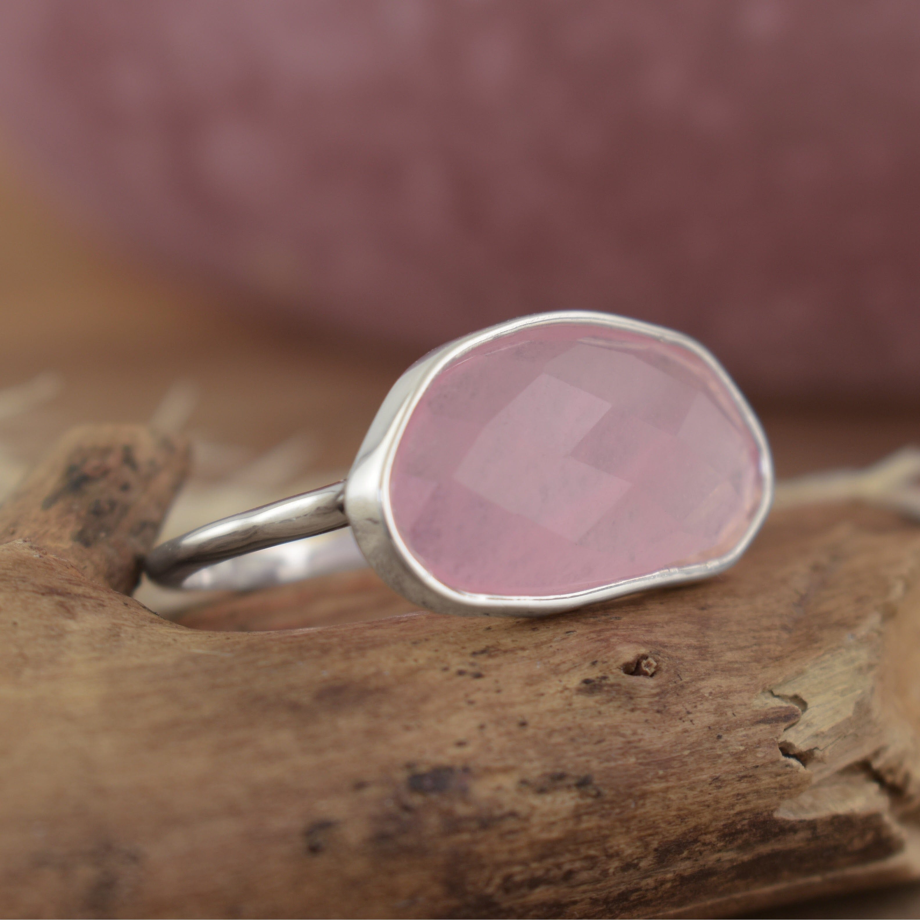A sterling silver ring with a large oval-shaped pink quartz stone in the center