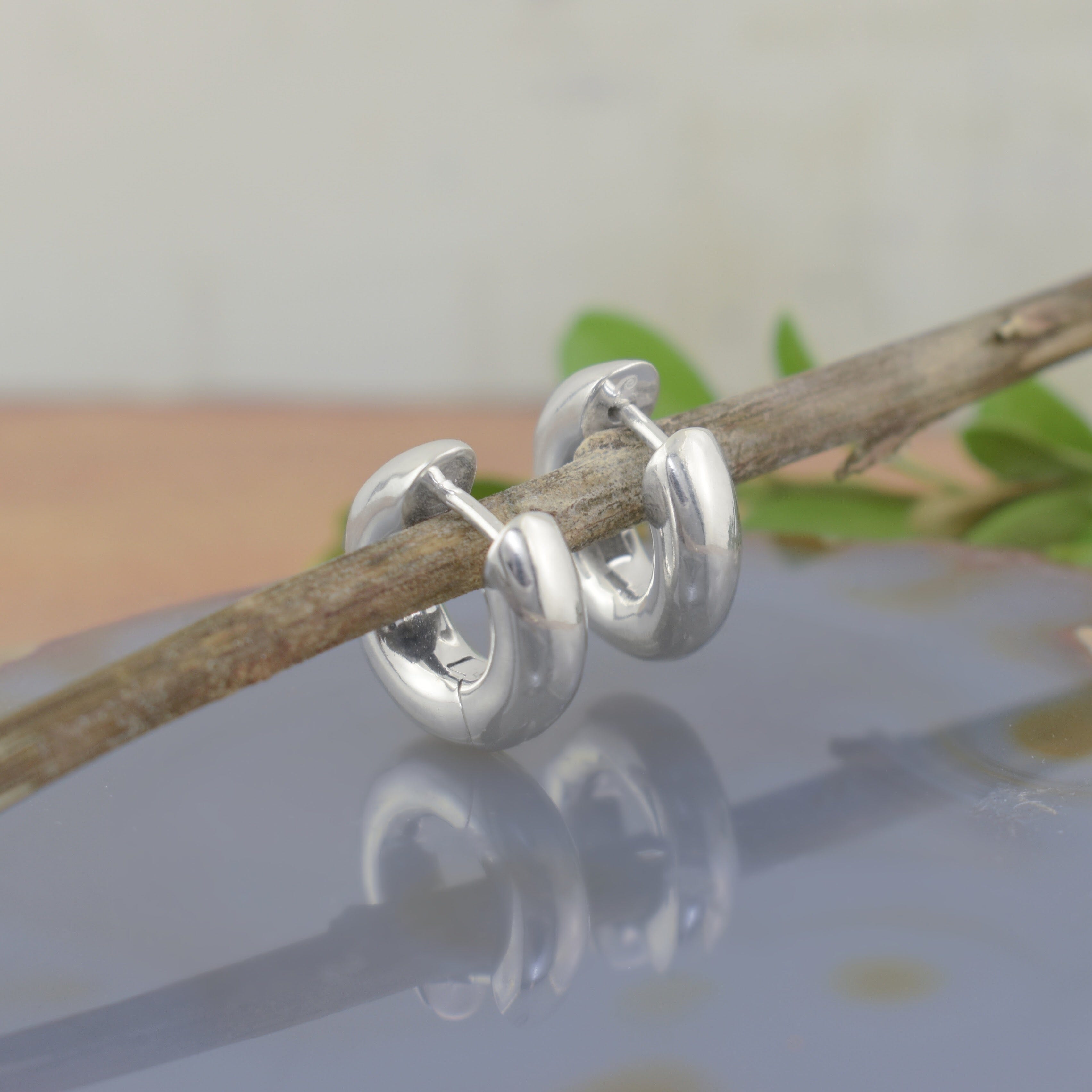 A pair of polished silver huggie hoop earrings