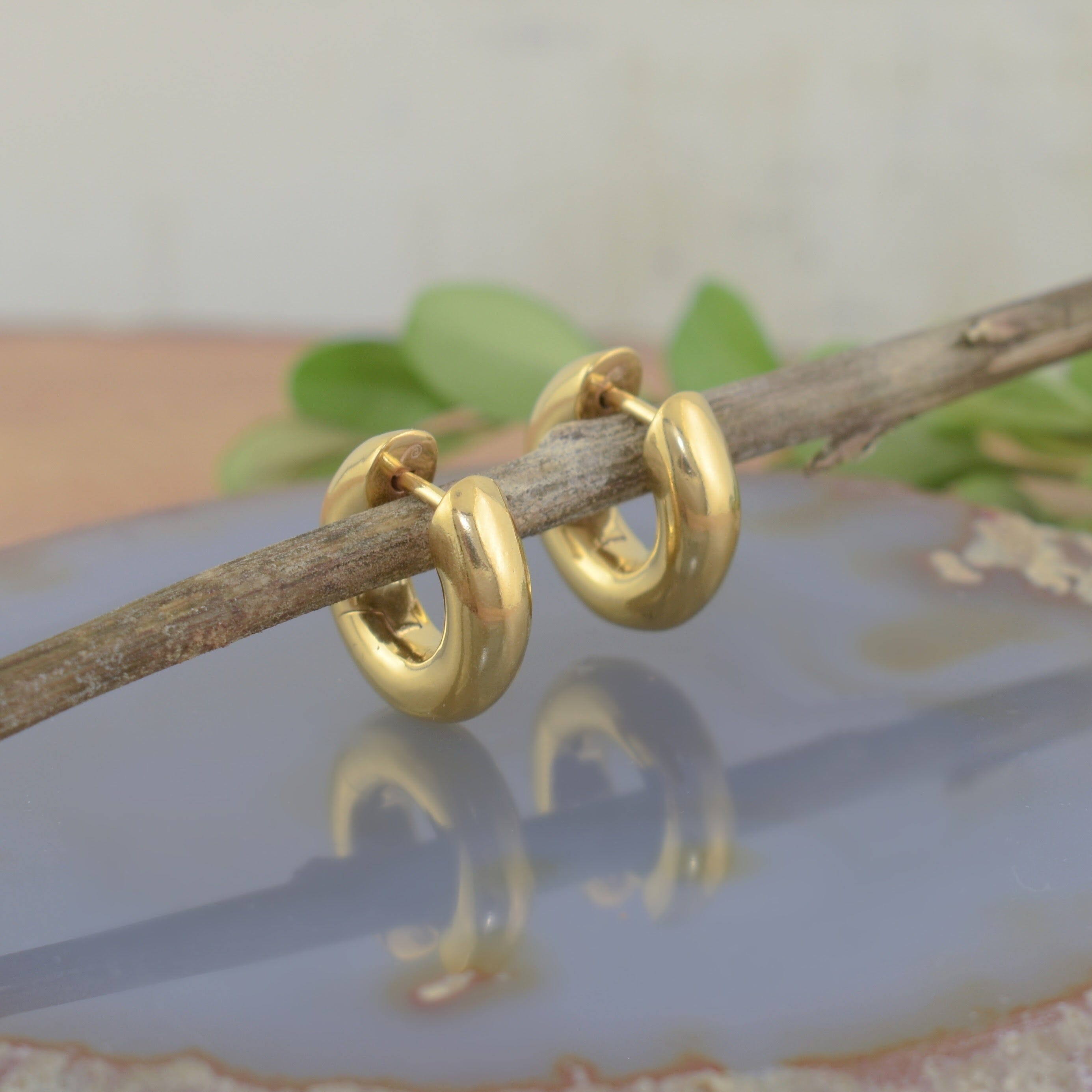 A small pair of polished gold huggie earrings