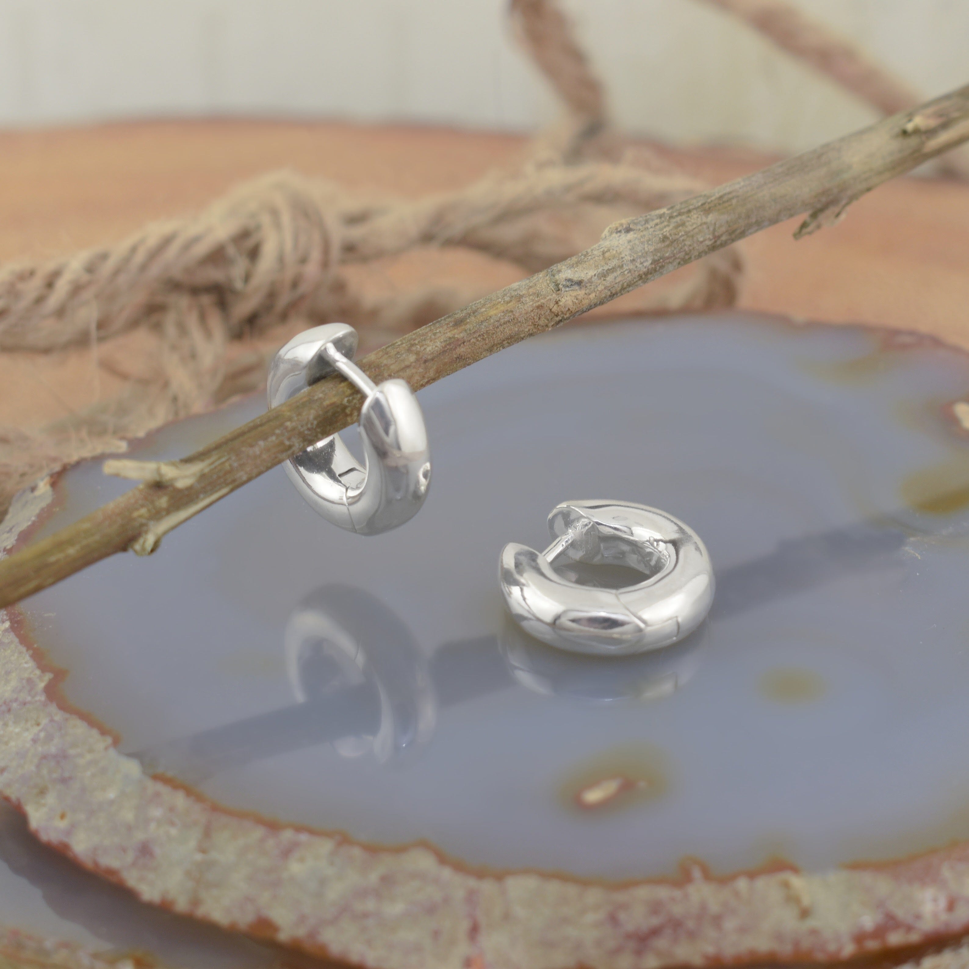 A pair of polished silver huggie hoop earrings