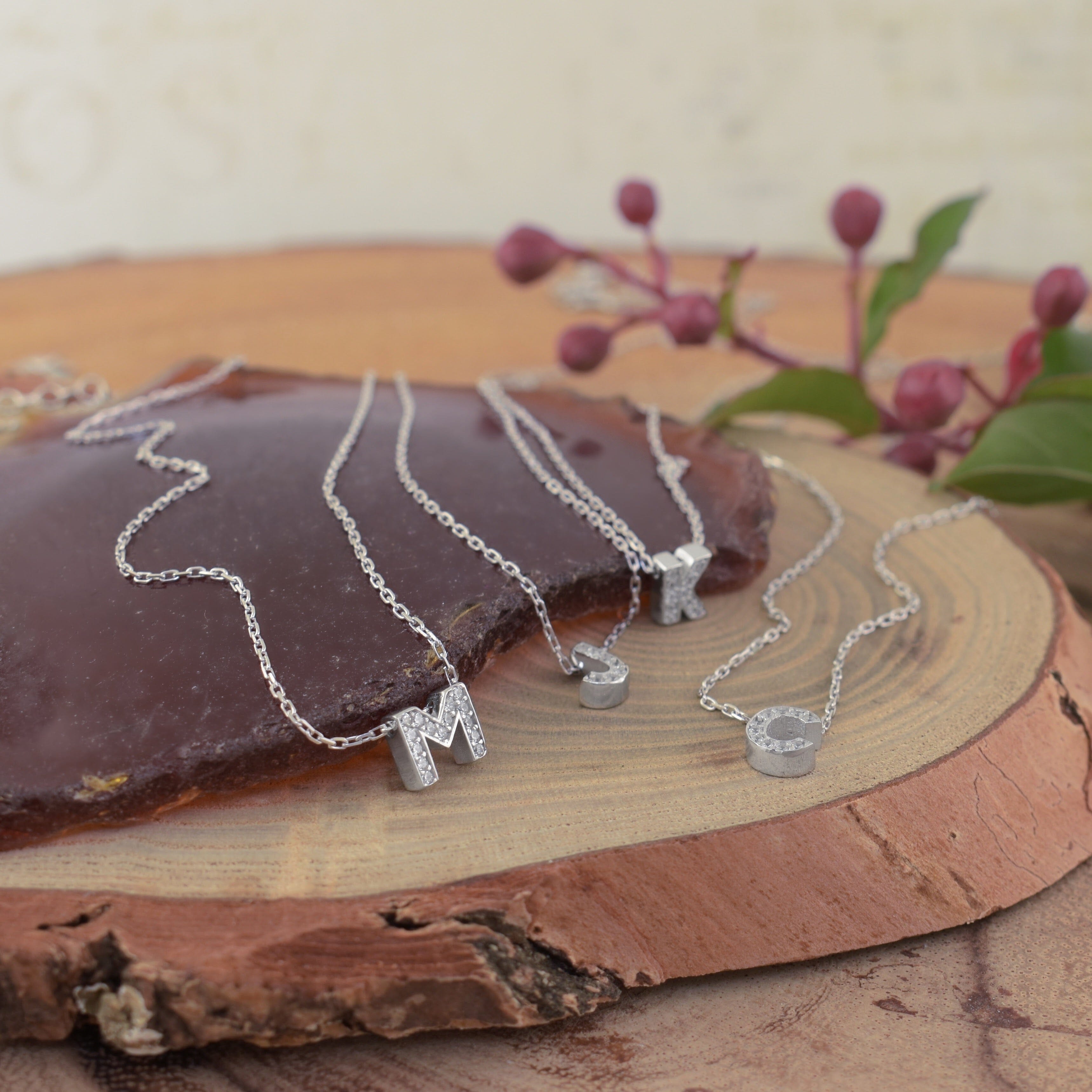 several sterling silver initial necklaces filled with clear CZ stones on one side