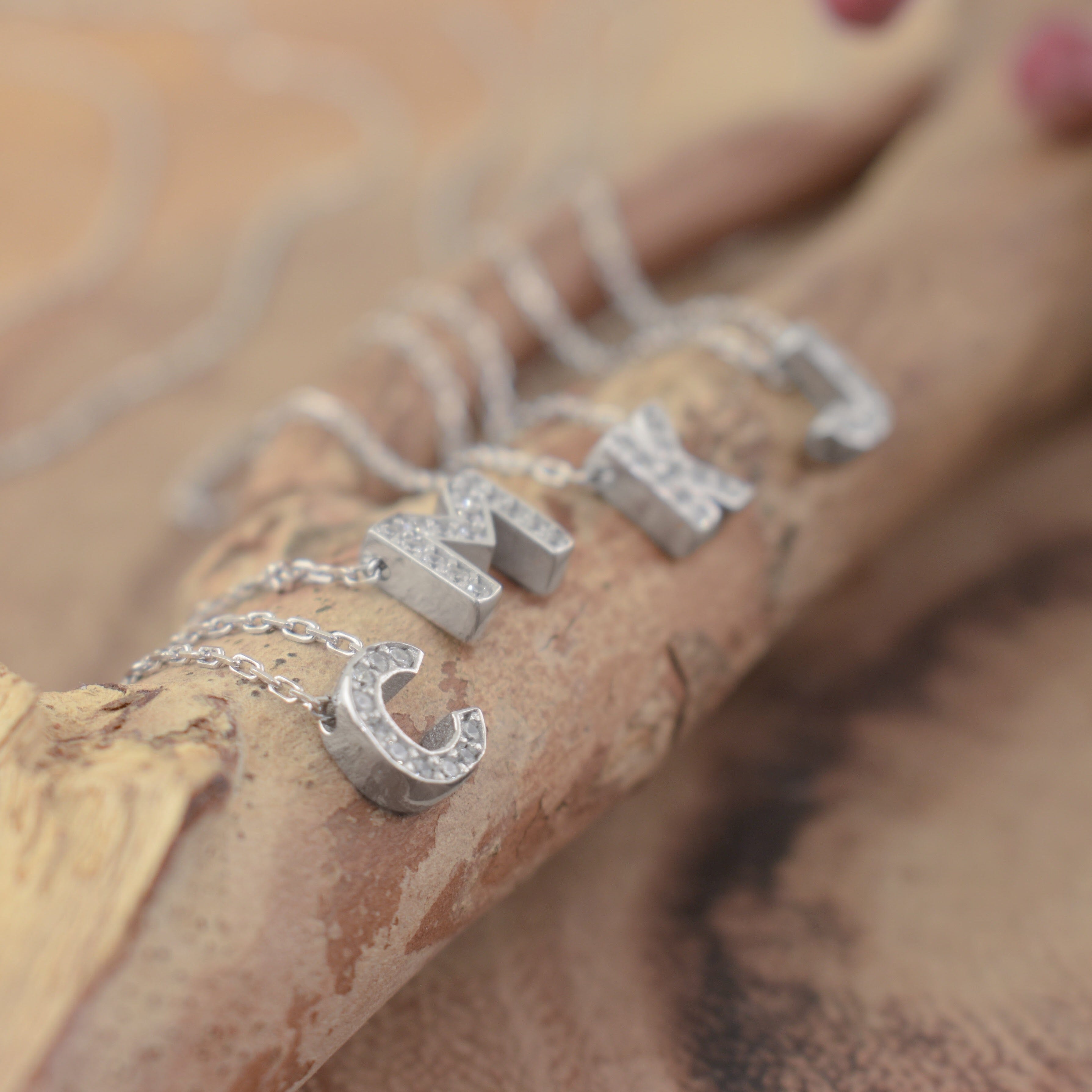 several sterling silver initial necklaces filled with clear CZ stones on one side