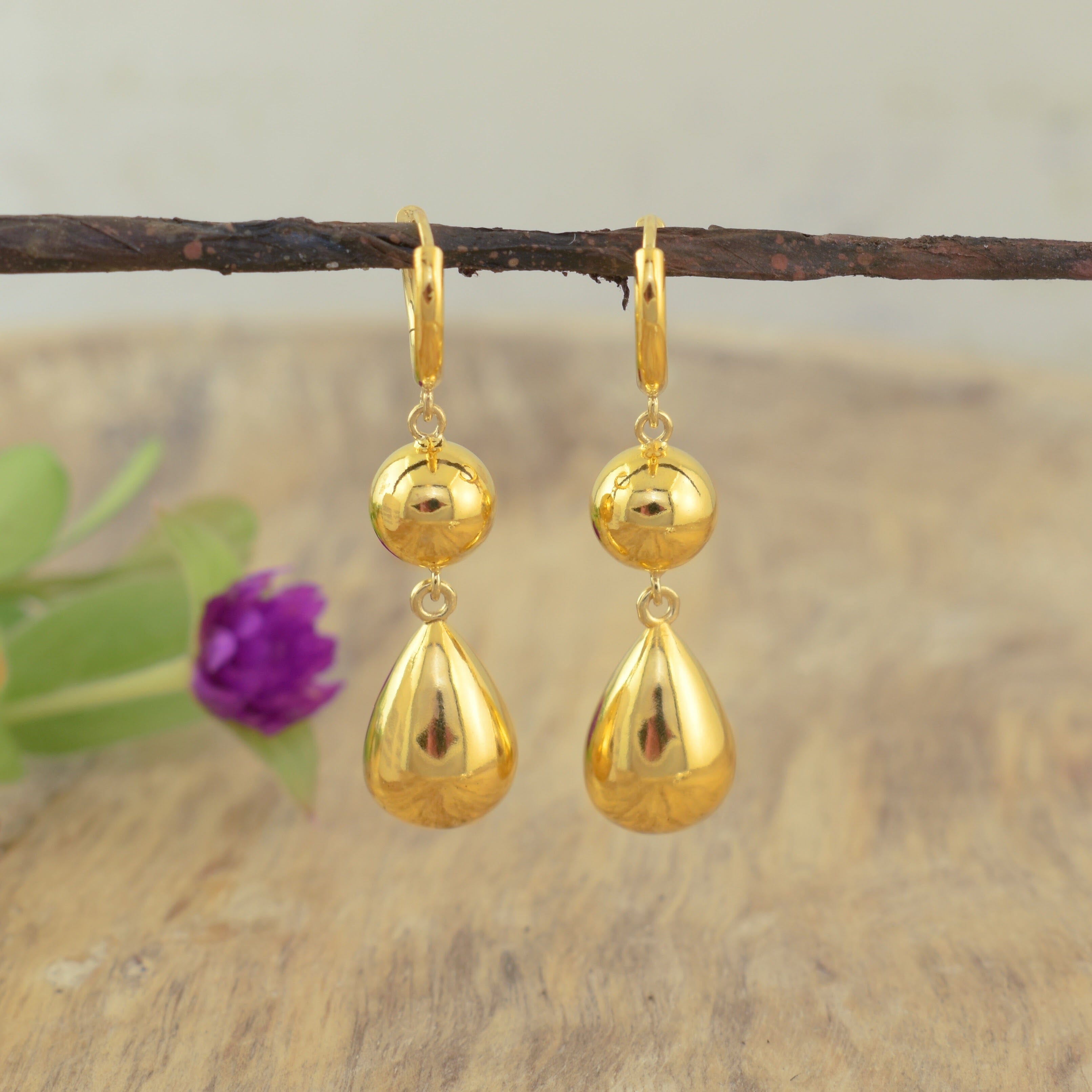 a pair of high polish gold huggie hoop drop earrings with polished spherical and teardrop charms