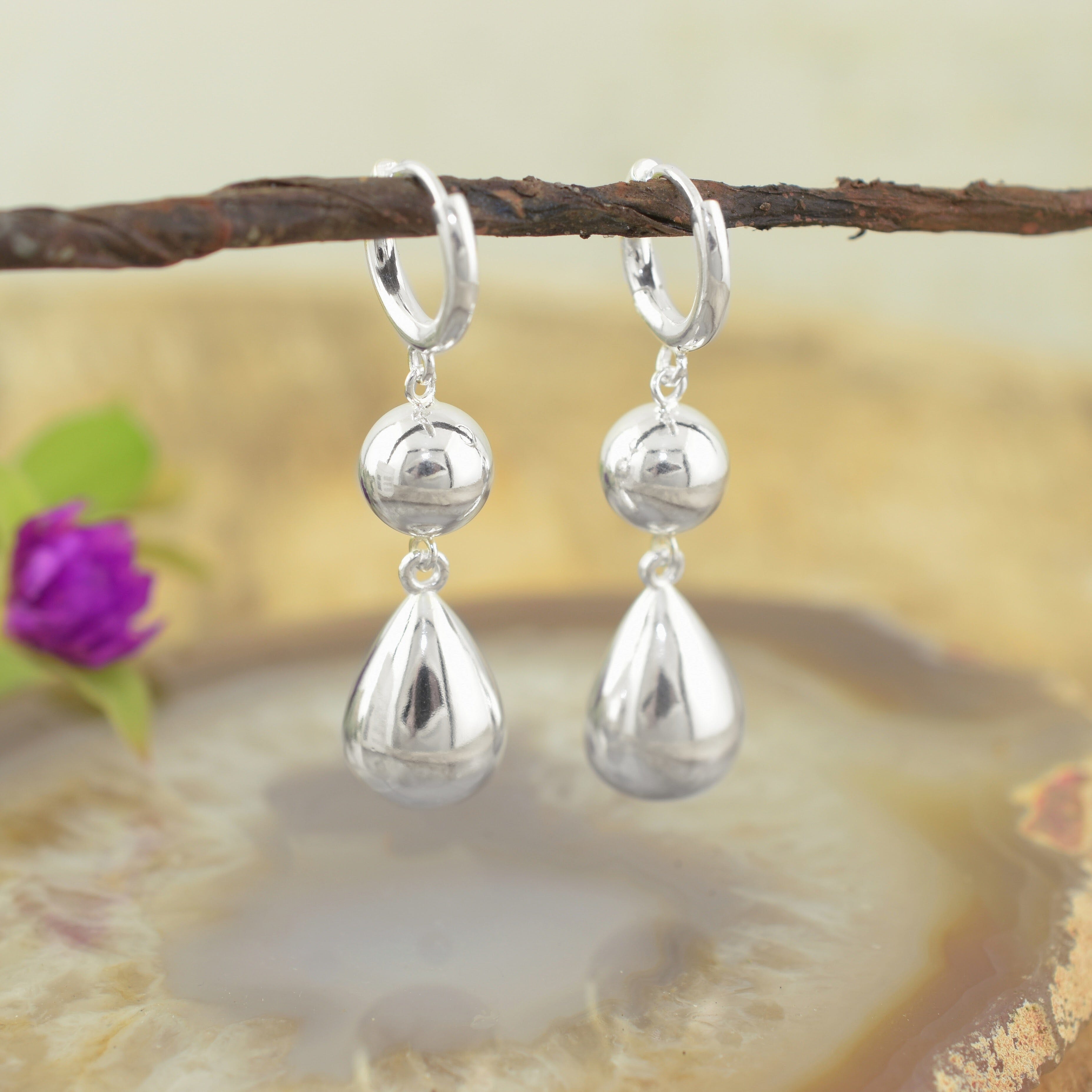 a pair of high polish silver huggie hoop drop earrings with polished spherical and teardrop charms