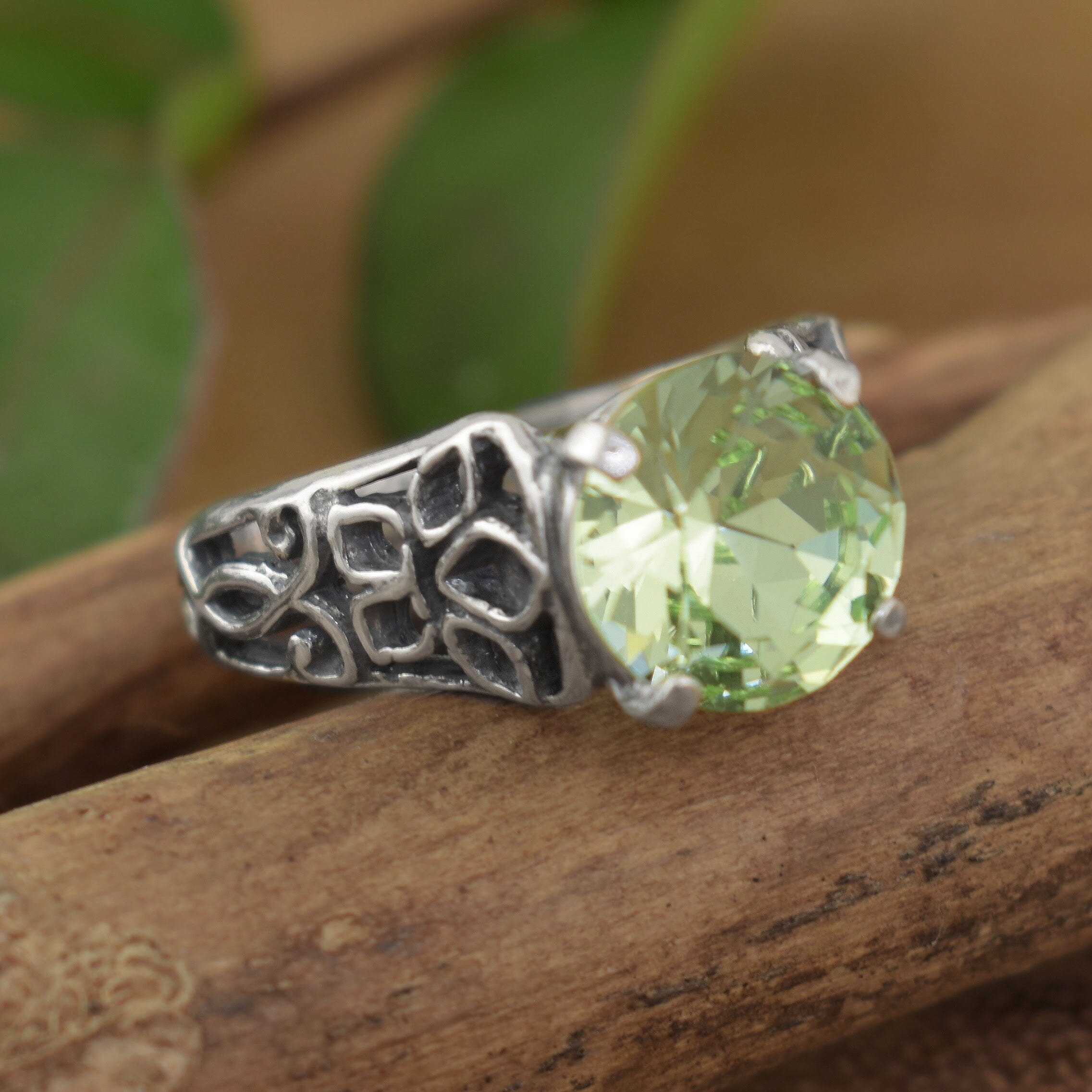 a silver ring with an ornate filigree band and a large round light green gemstone