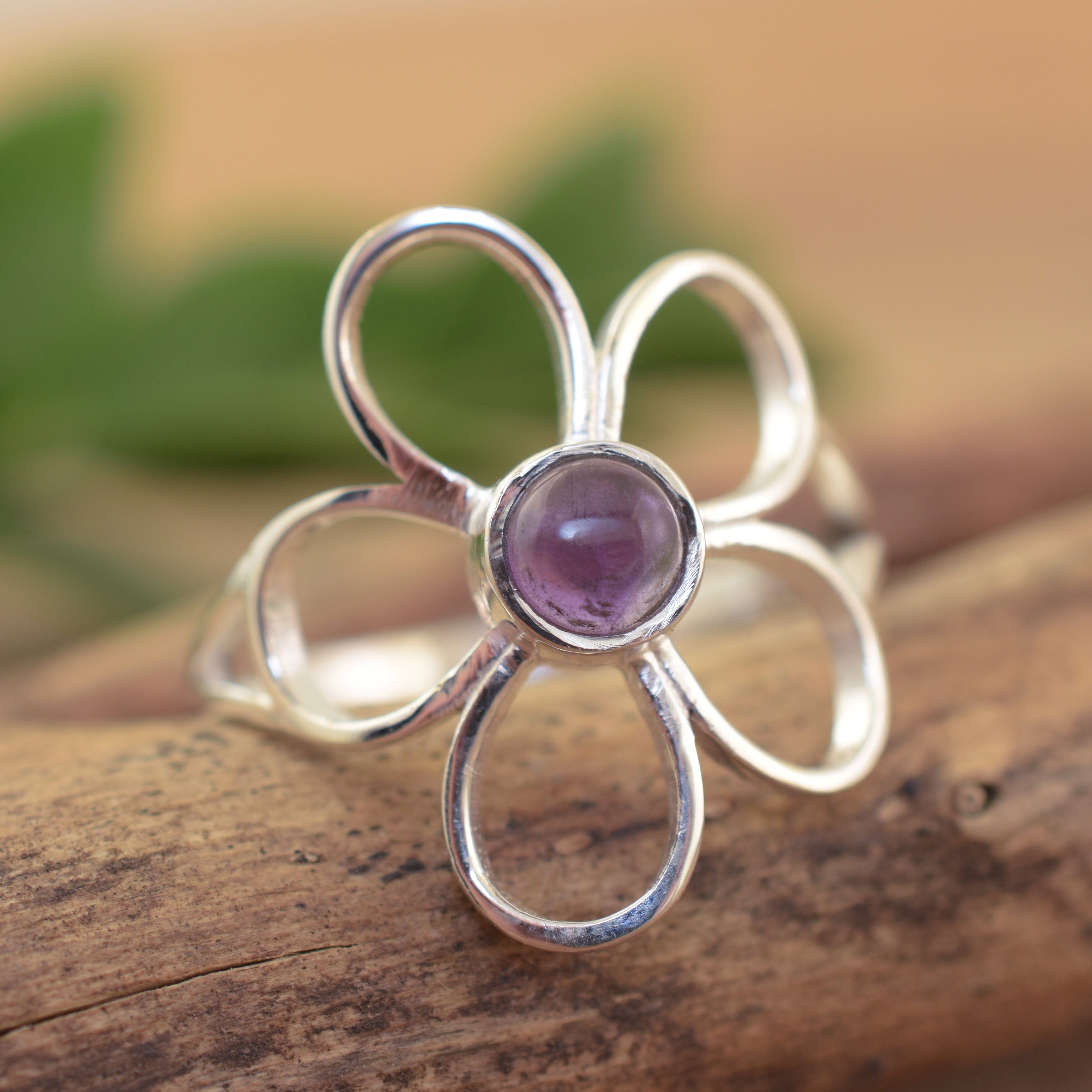 A sterling silver ring featuring a large flower with an amethyst stone in the center