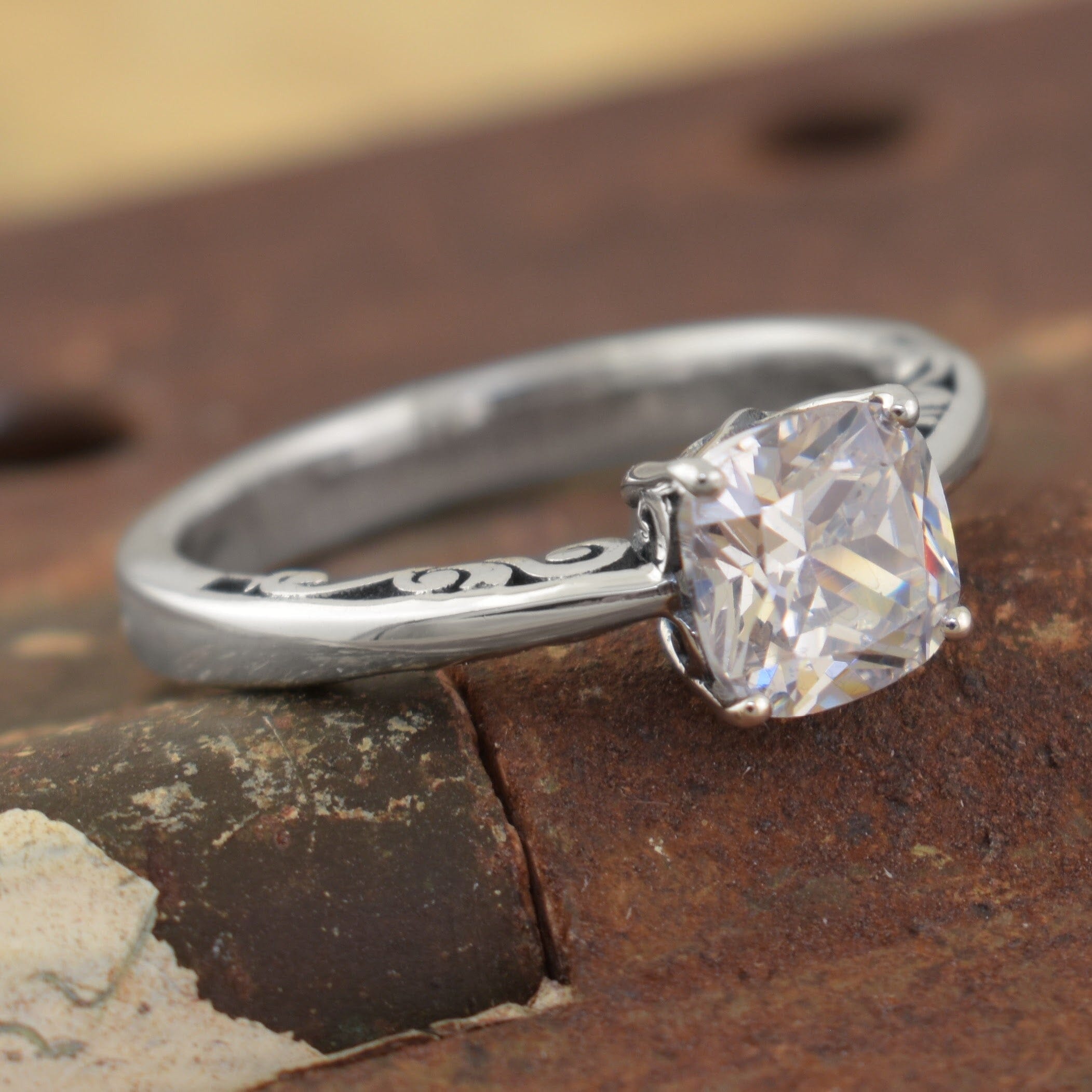 a sterling silver ring with an engraved band and a square-cut clear gemstone