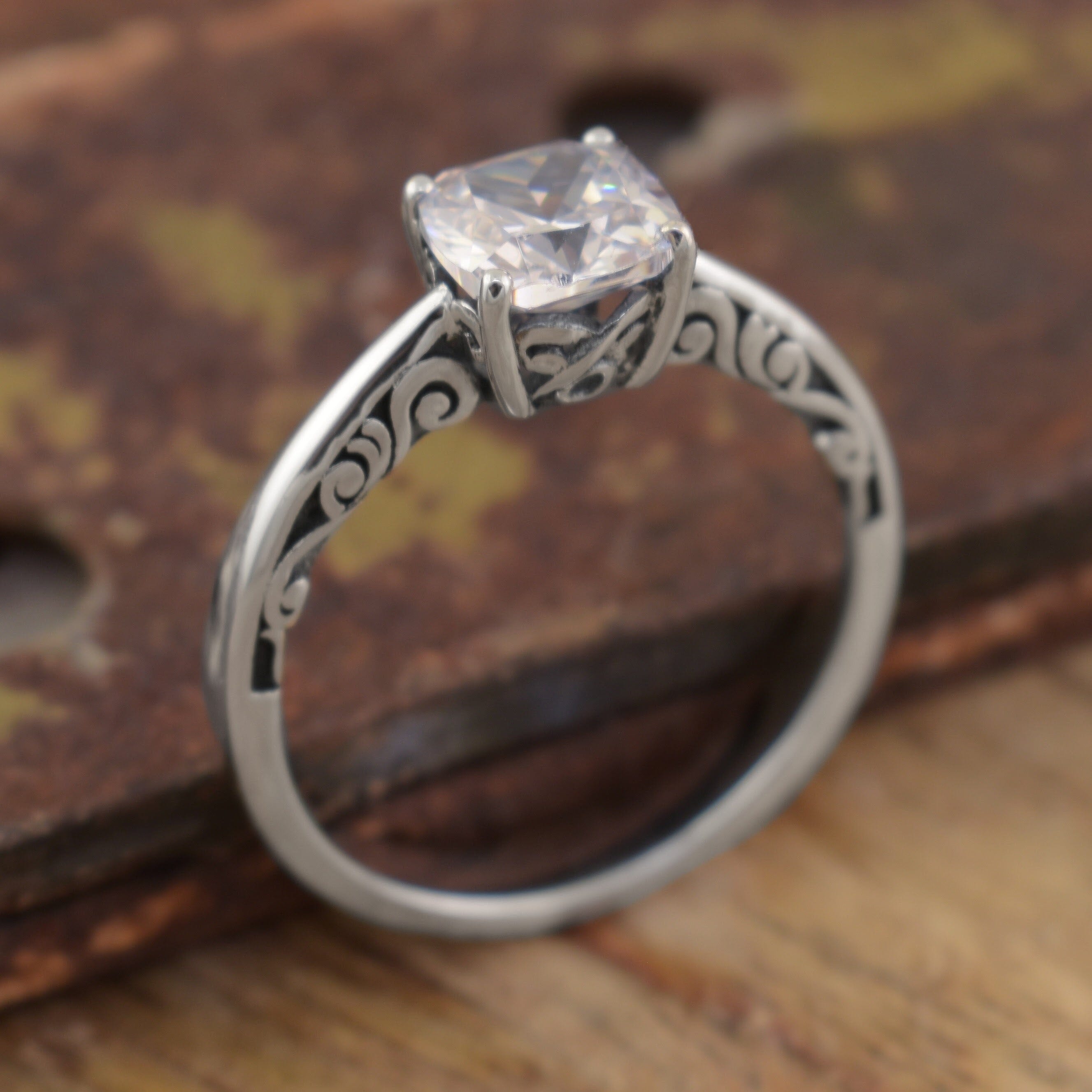 a handcrafted sterling silver solitaire ring with a square-cut clear CZ and engraved filigree on the sides