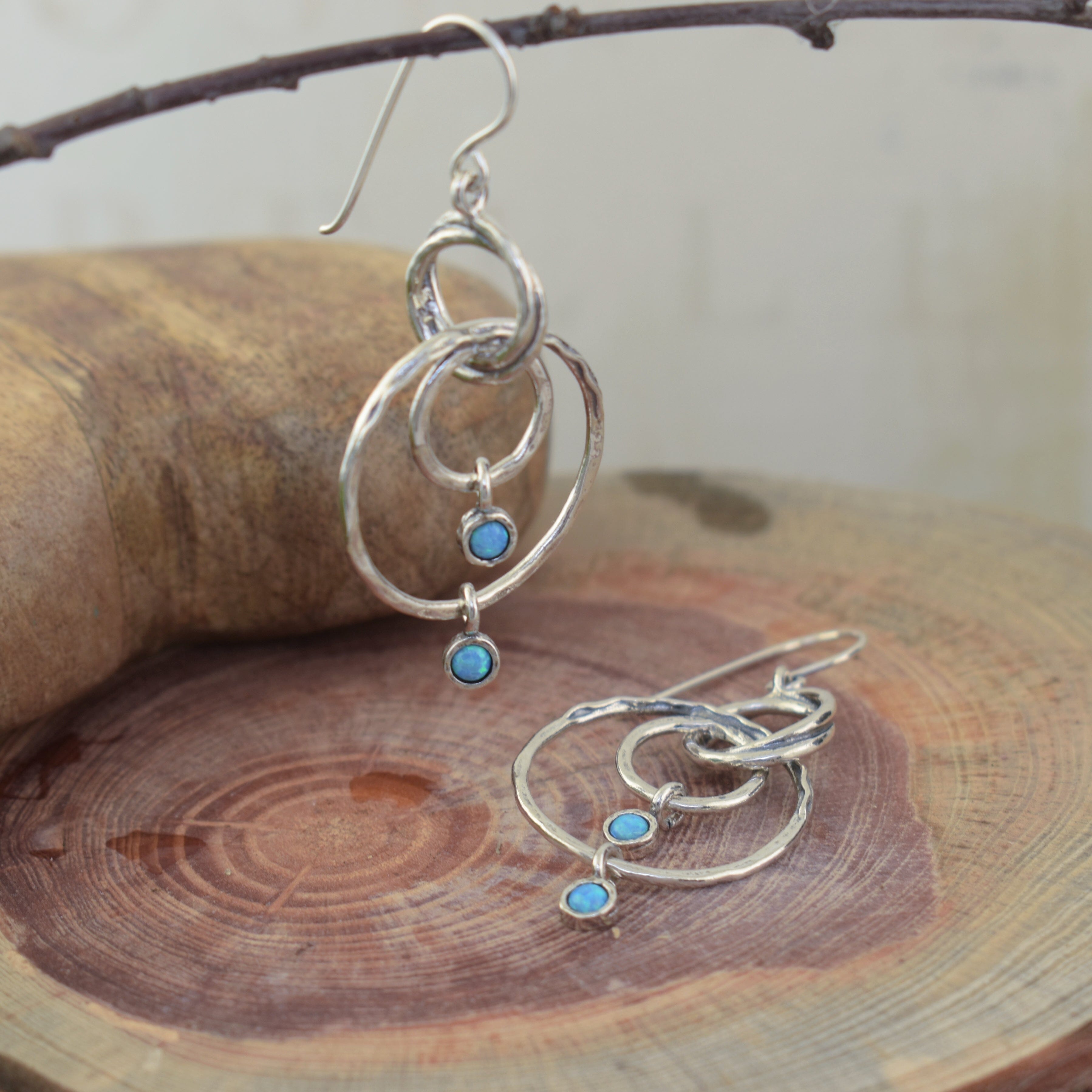 Circular sterling silver earrings featuring blue stone dangles
