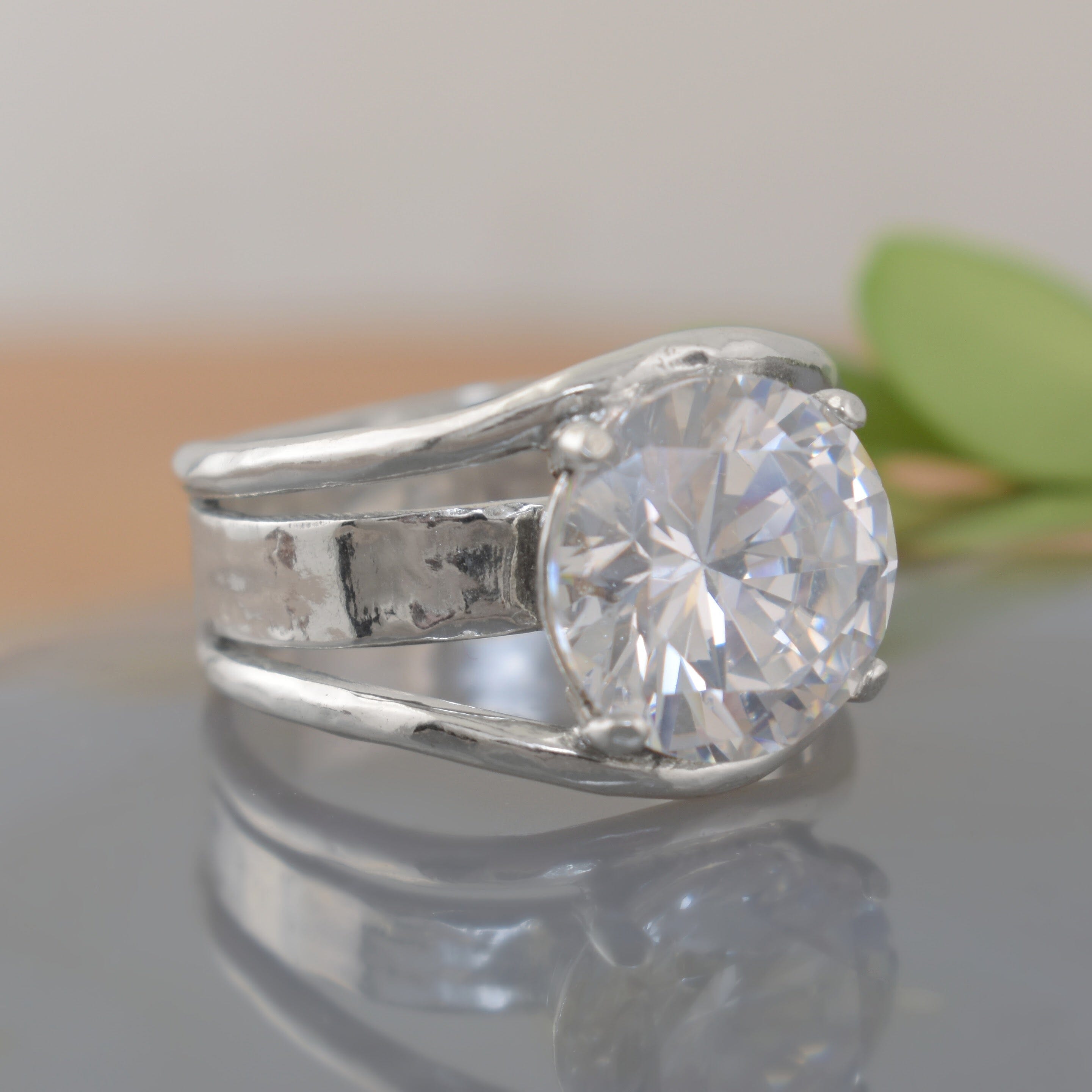 A sterling silver ring featuring a large clear CZ with cut outs in the band
