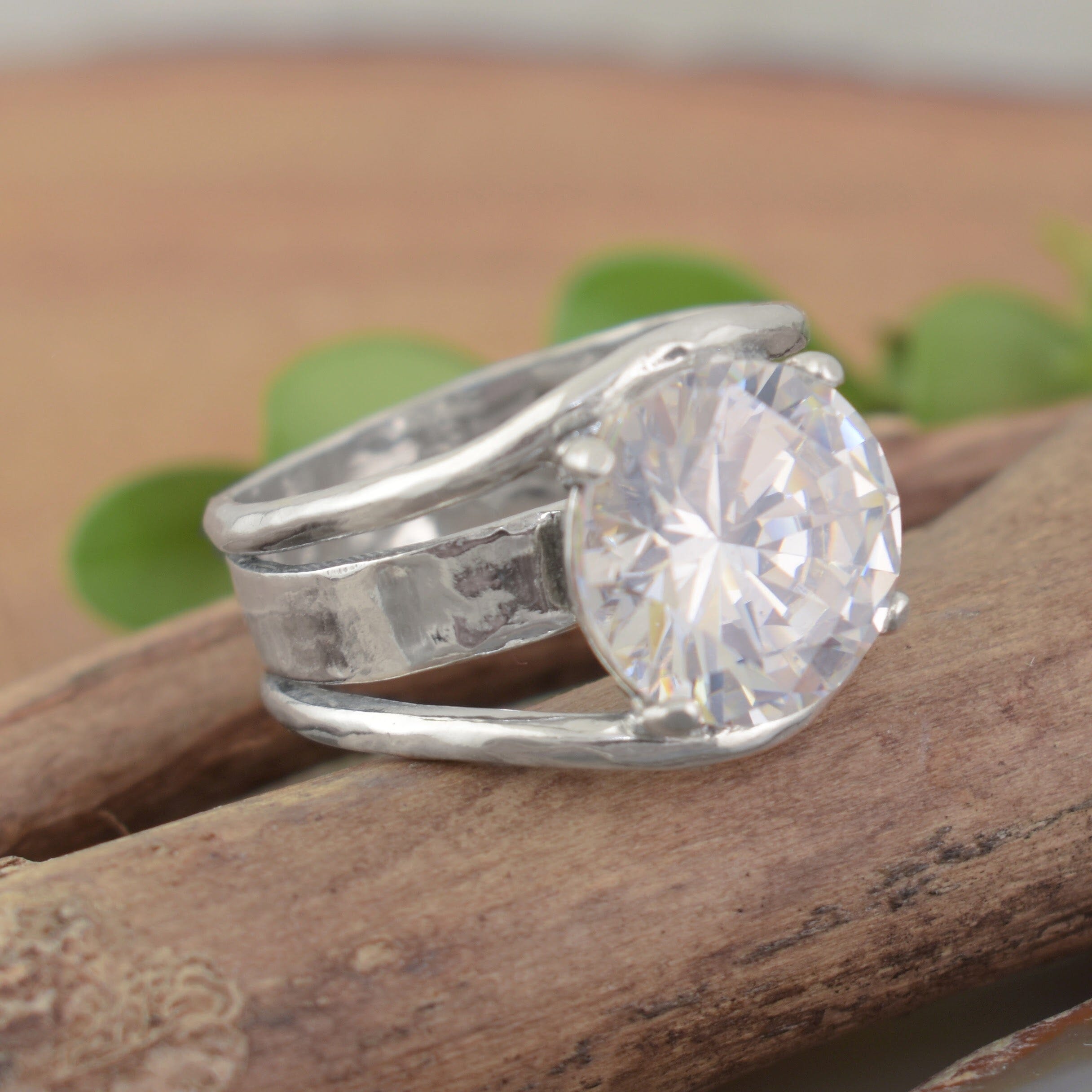 A sterling silver ring featuring a faceted large round clear CZ with cut outs in the band