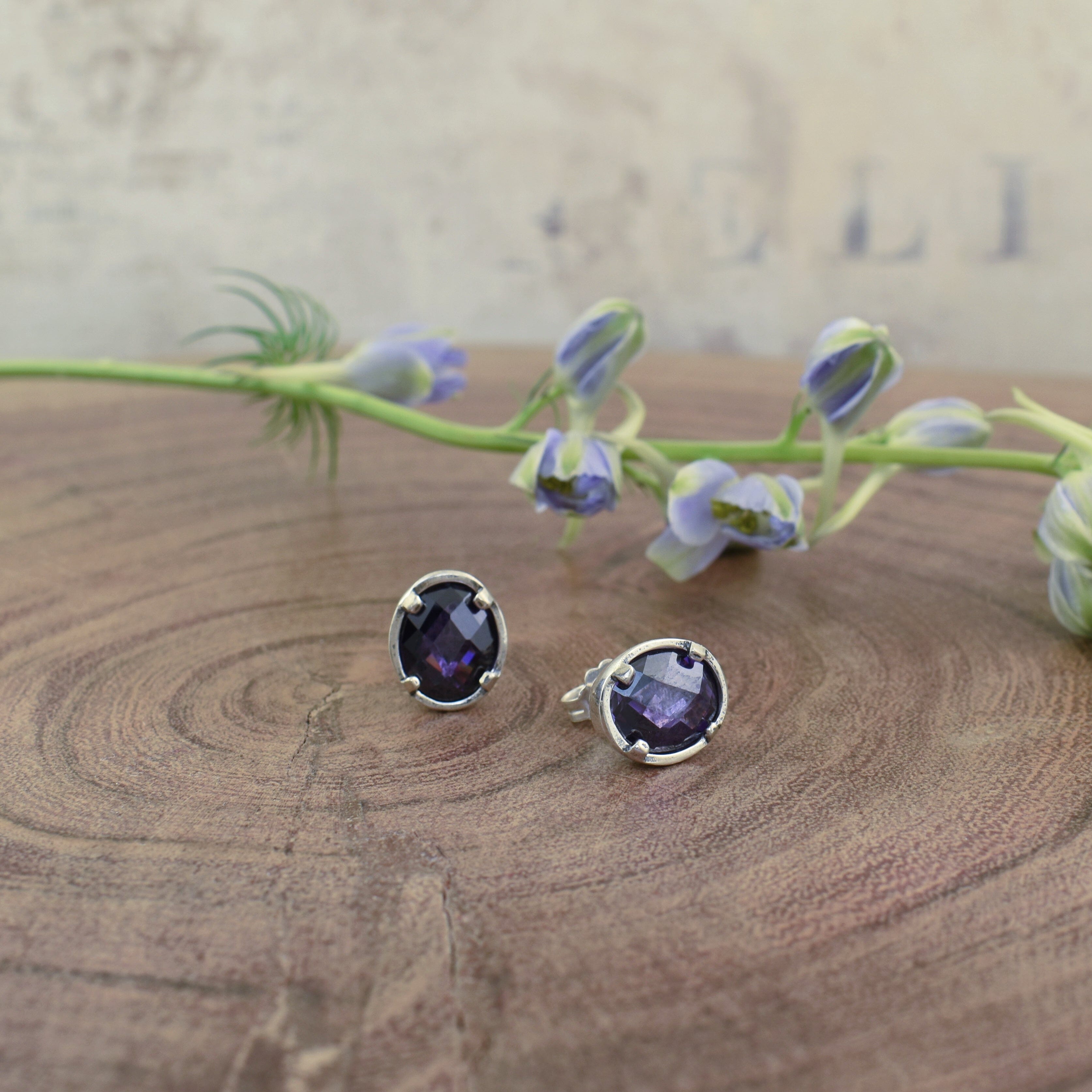 push back post earrings with an oval purple colored stone