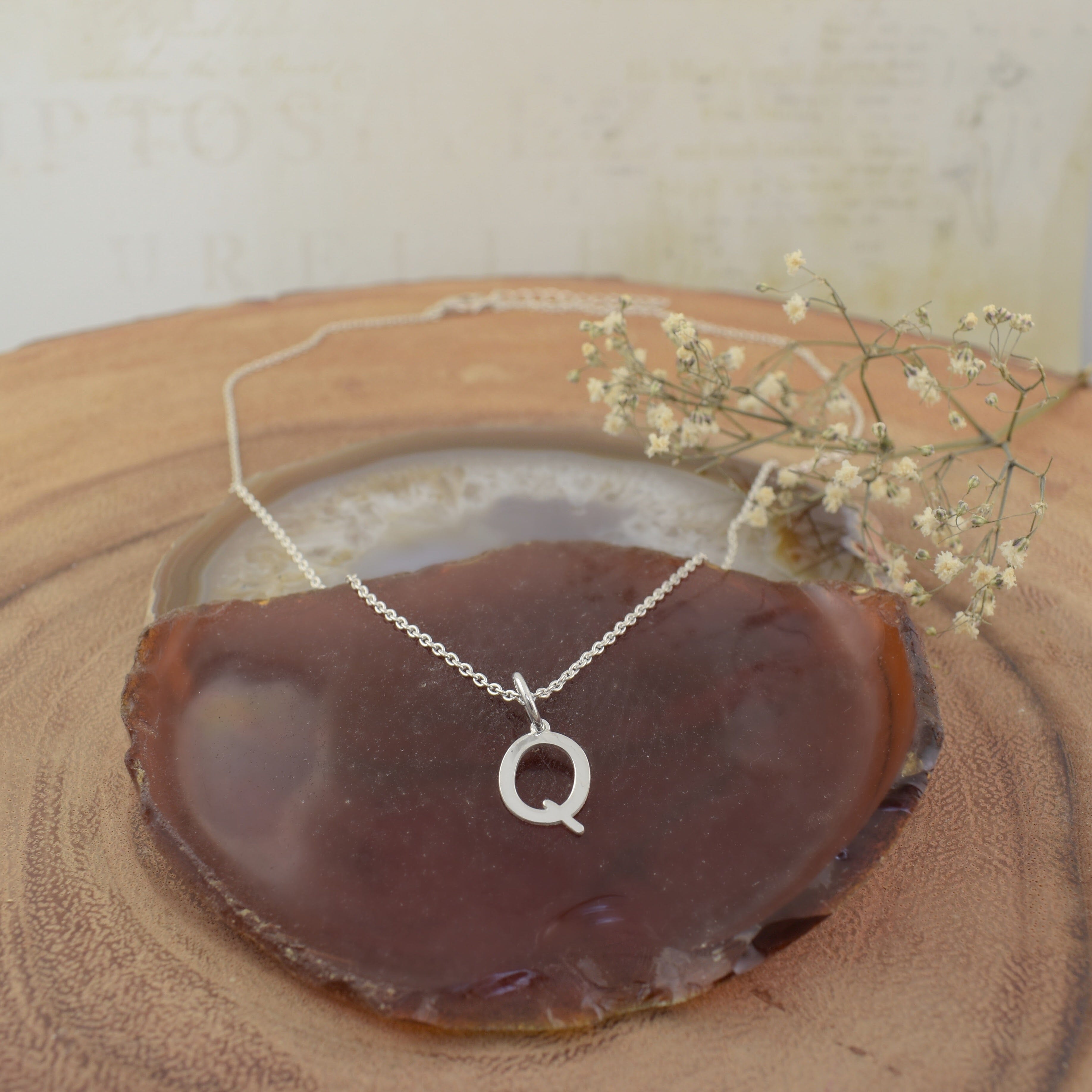 A sterling silver necklace featuring an initial pendant "Q"