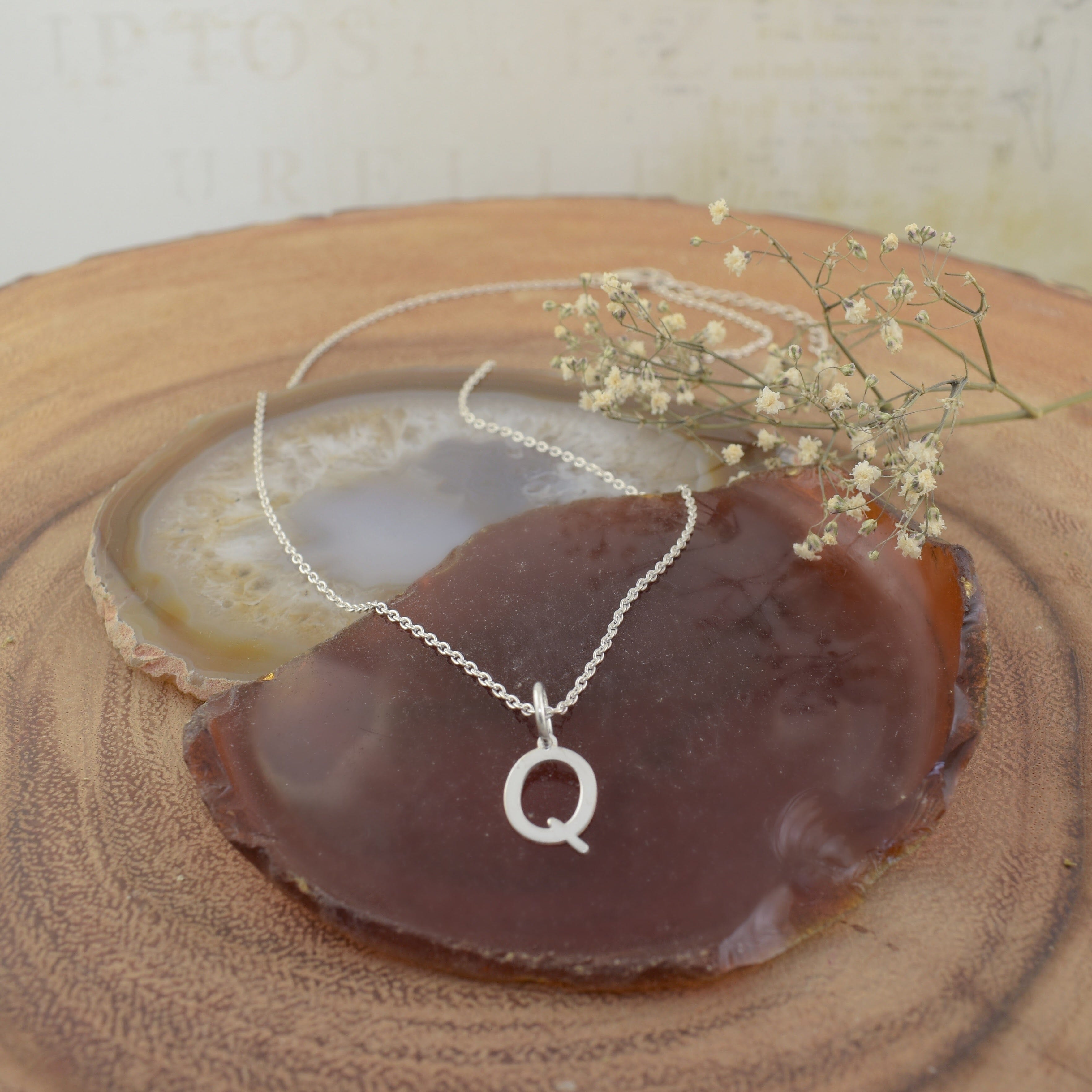 A sterling silver necklace featuring an initial pendant "Q"